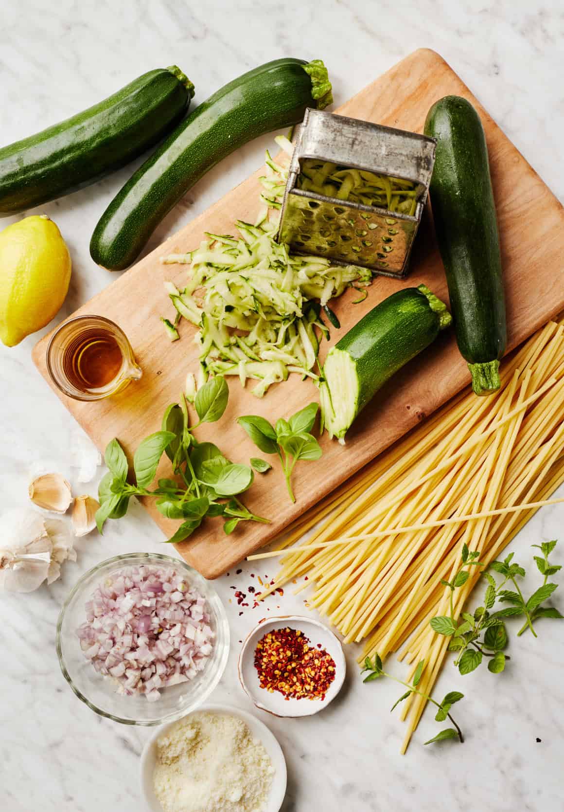 Recipe ingredients - spaghetti, grated summer squash, shallots, garlic, lemon, and fresh herbs