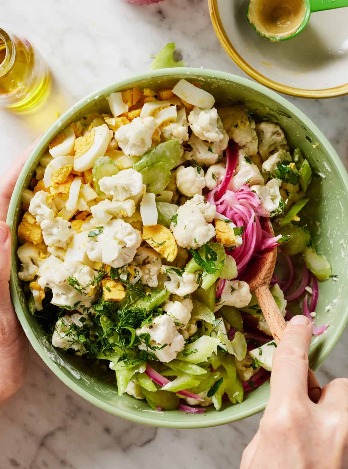 Mixing cauliflower salad in bowl with wooden spoon