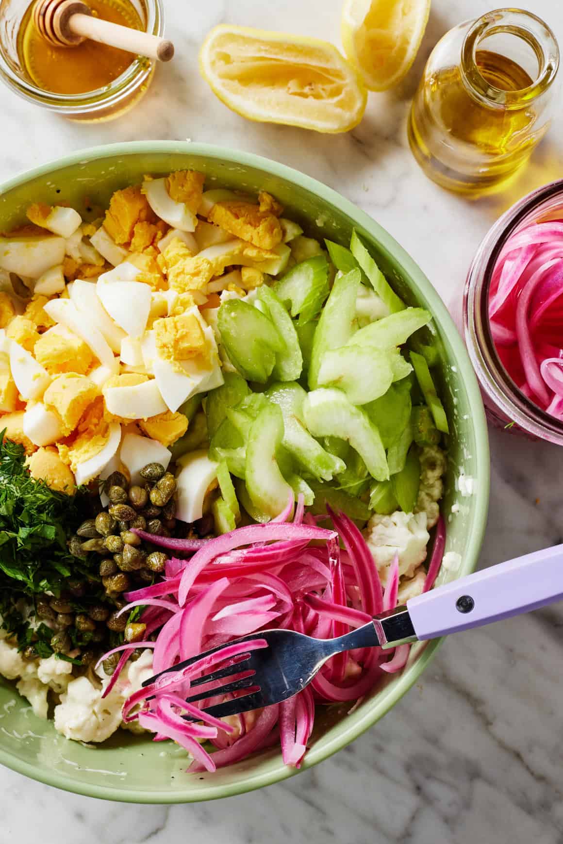 Celery, red onions, hard boiled eggs, capers, and herbs in mixing bowl