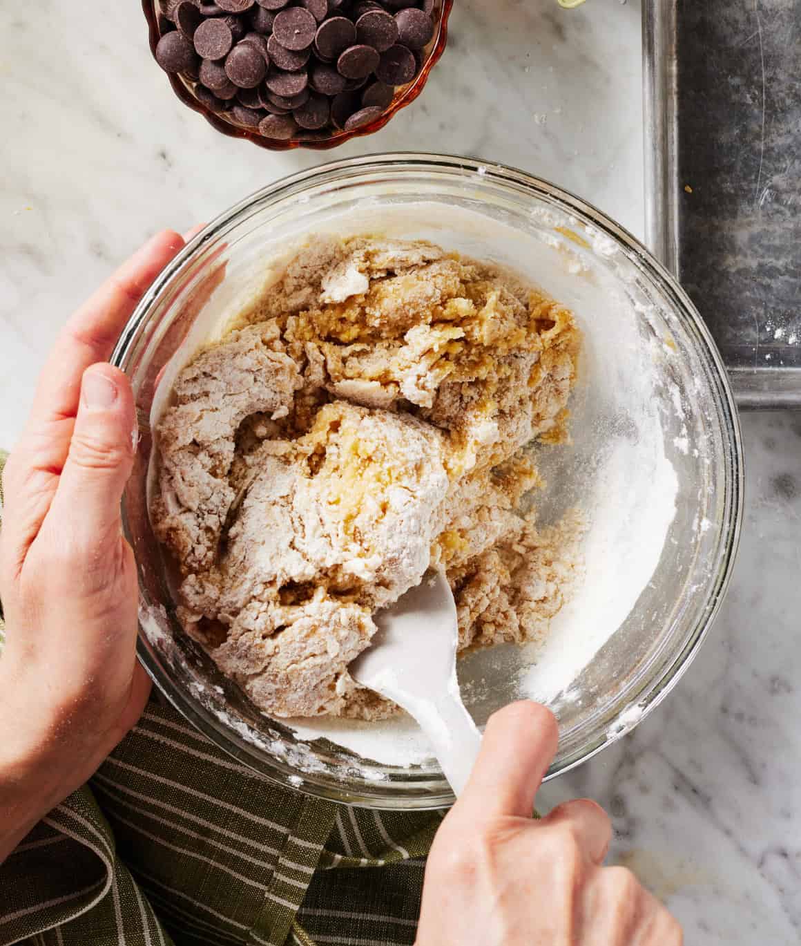 Using spatula to mix chocolate chip cookie dough in glass bowl