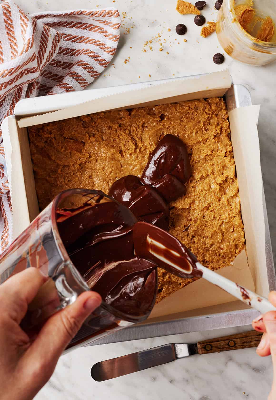 Pouring melted chocolate over peanut butter layer