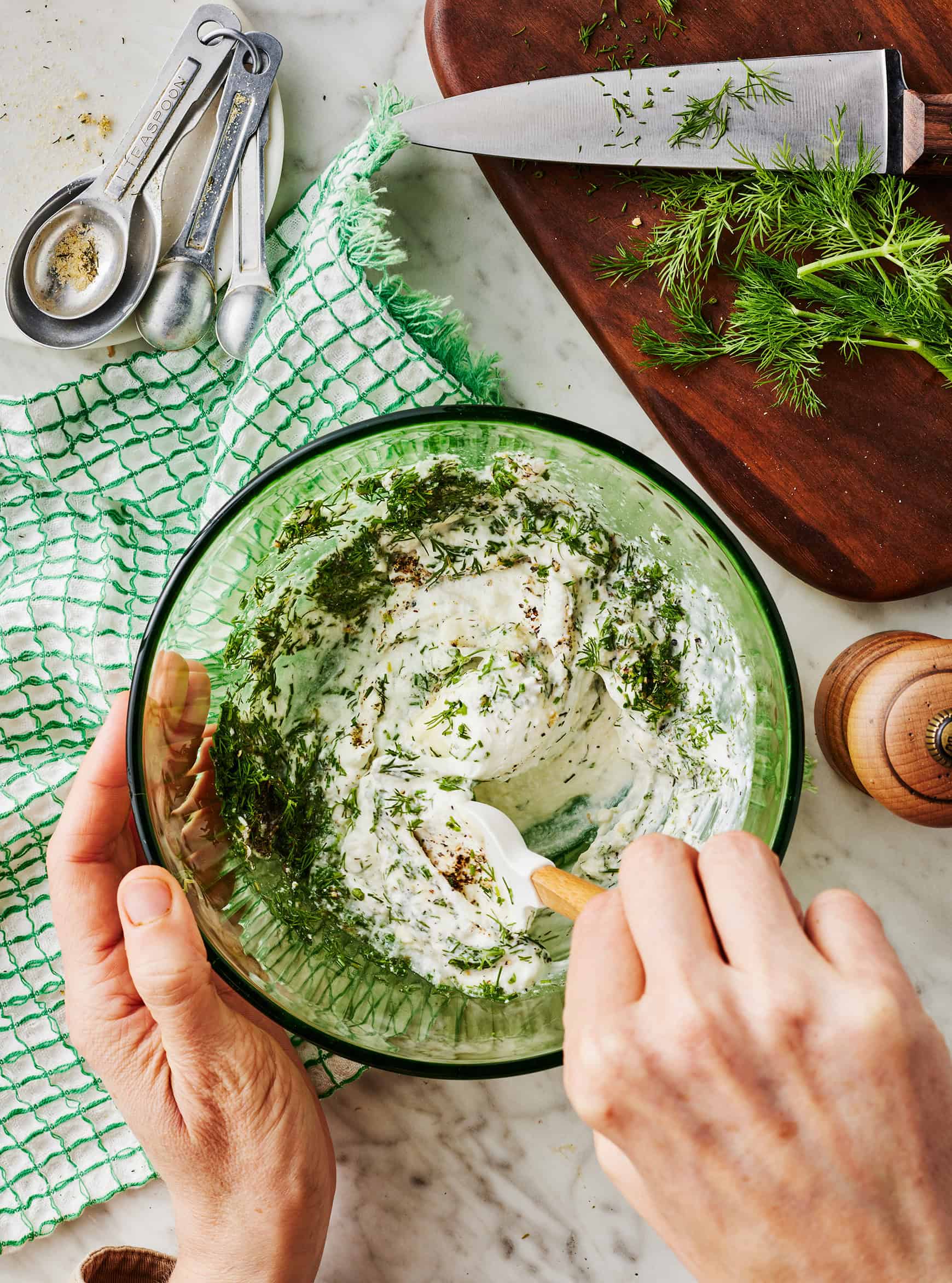 Stirring together sour cream, mayo, and dill in mixing bowl