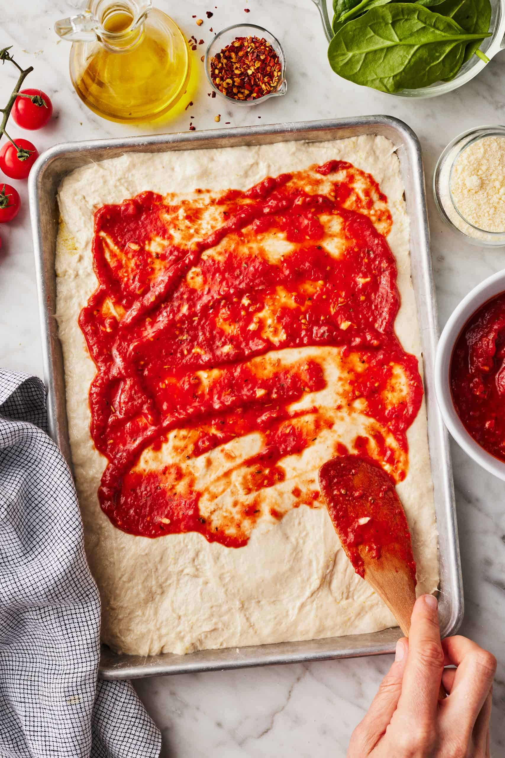 Spreading tomato sauce on dough