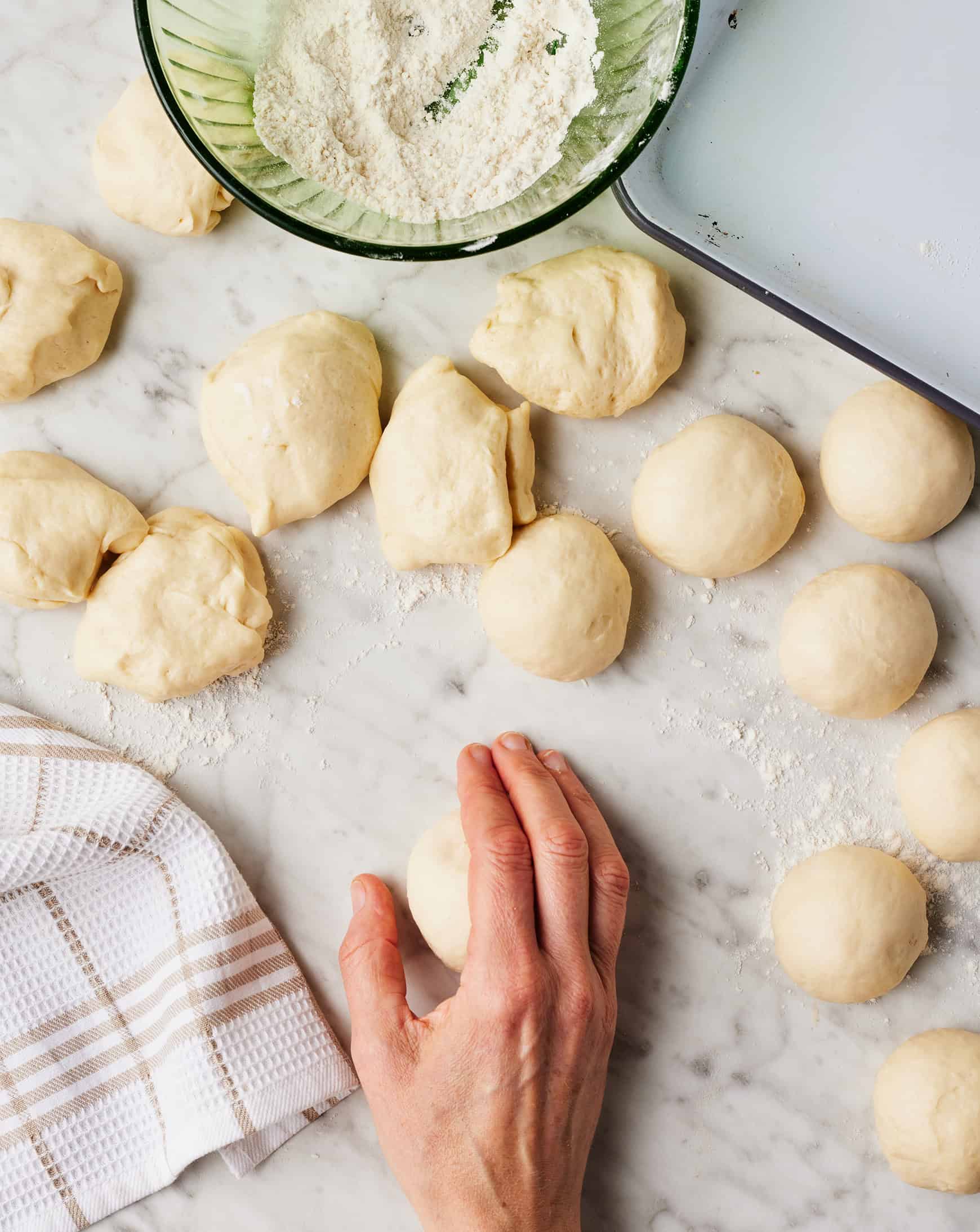 Hand shaping dinner rolls on floured surface