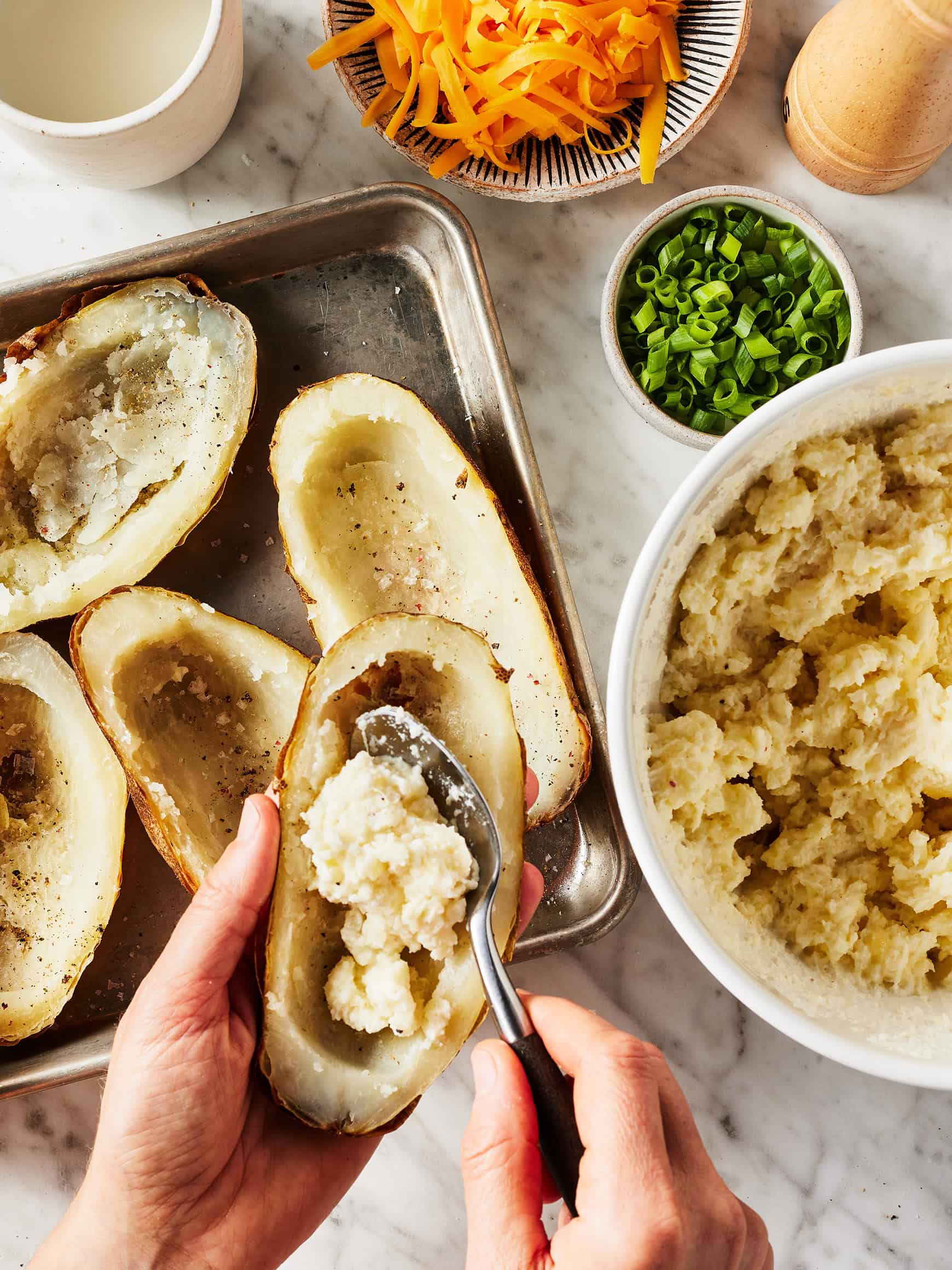 Spooning creamy filling into potato skins