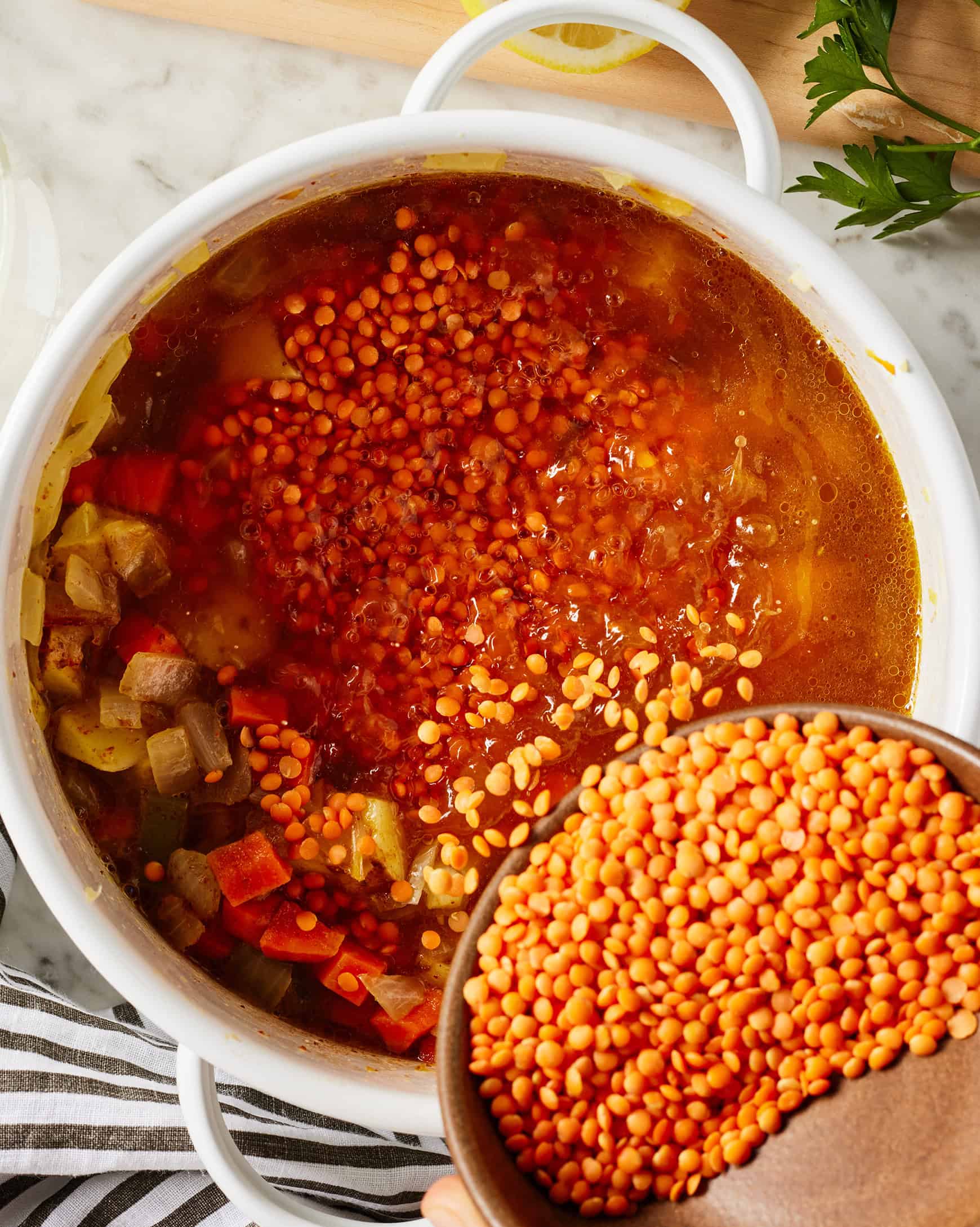 Adding red lentils to pot of soup