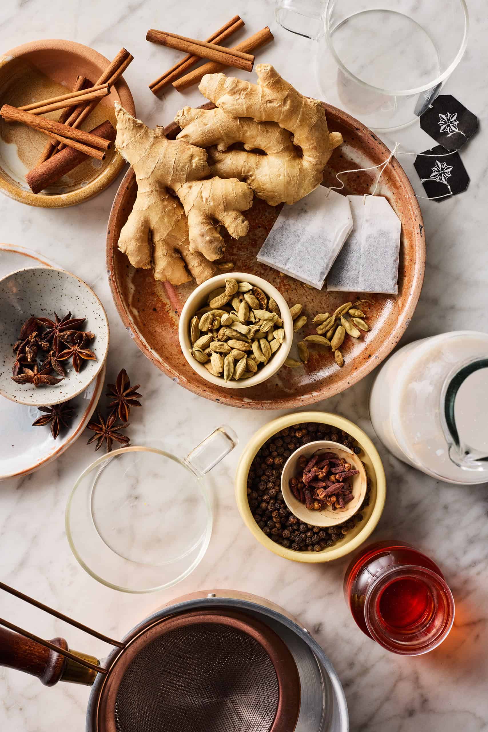 Chai latte recipe ingredients: whole spices, ginger, black tea bags, milk, and maple syrup