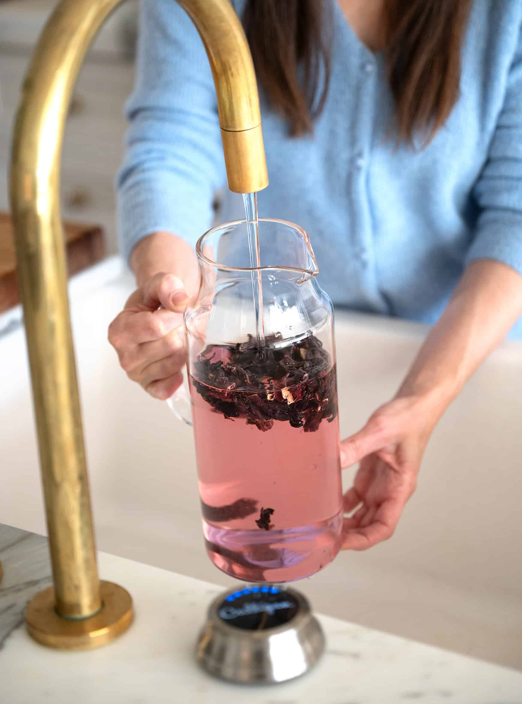 Adding filtered Culligan water to pitcher with hibiscus flowers