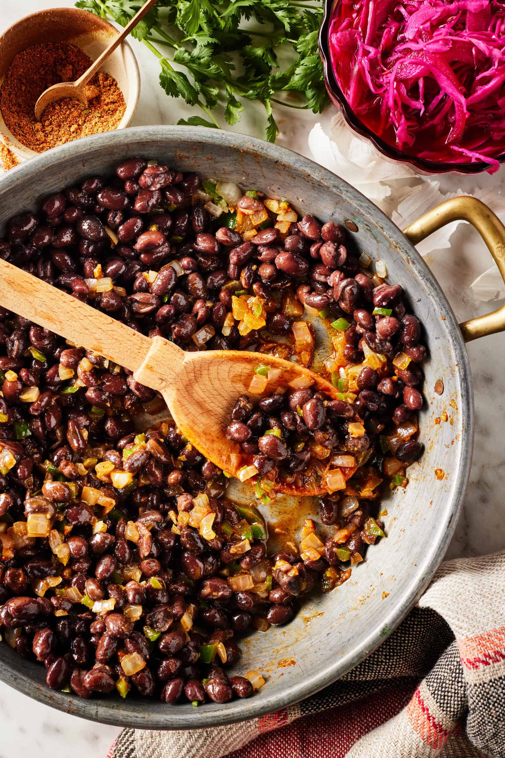 Cooking black beans in skillet with onions, jalapenos, and spices