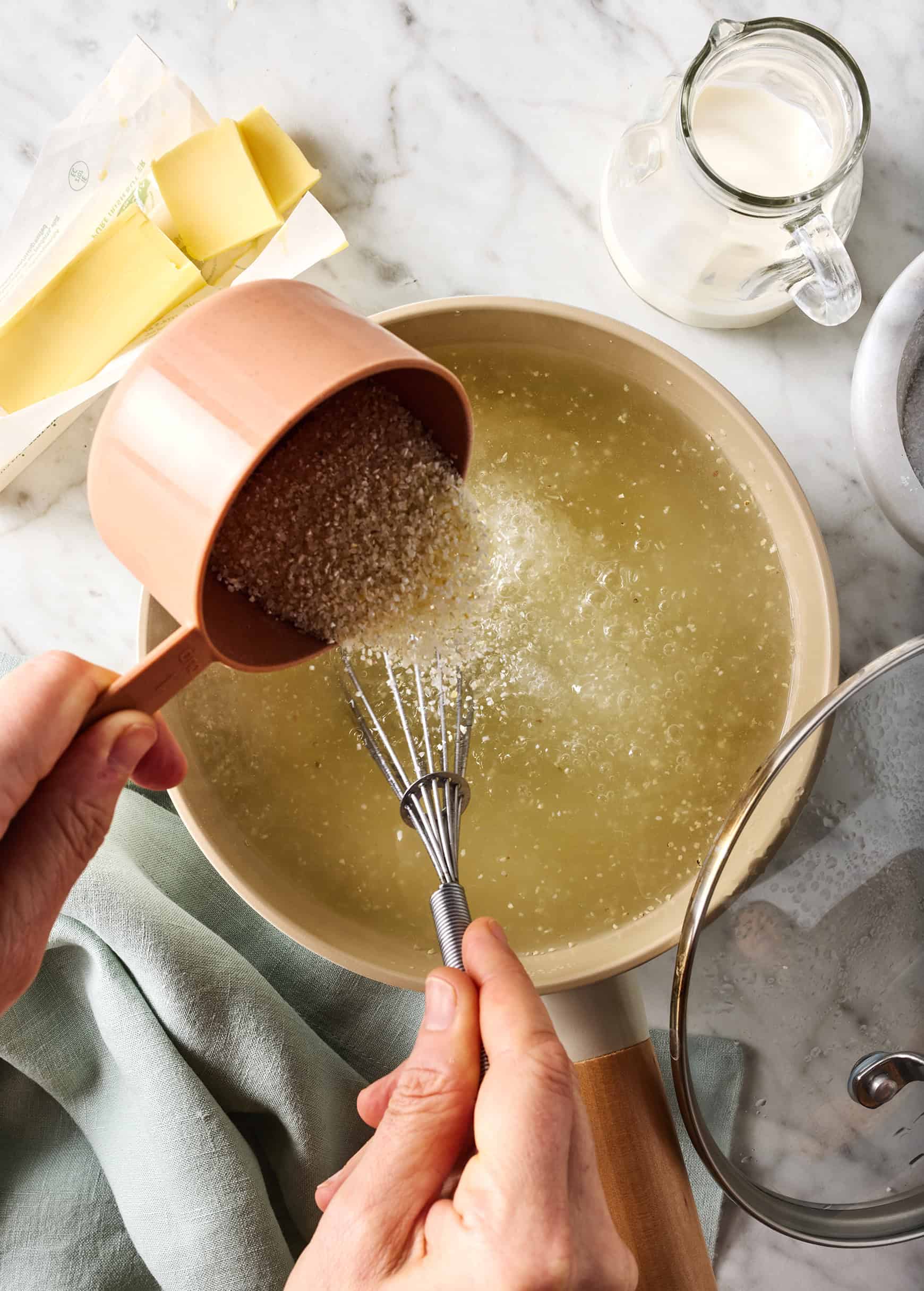 Pouring grits into pot of boiling water while whisking