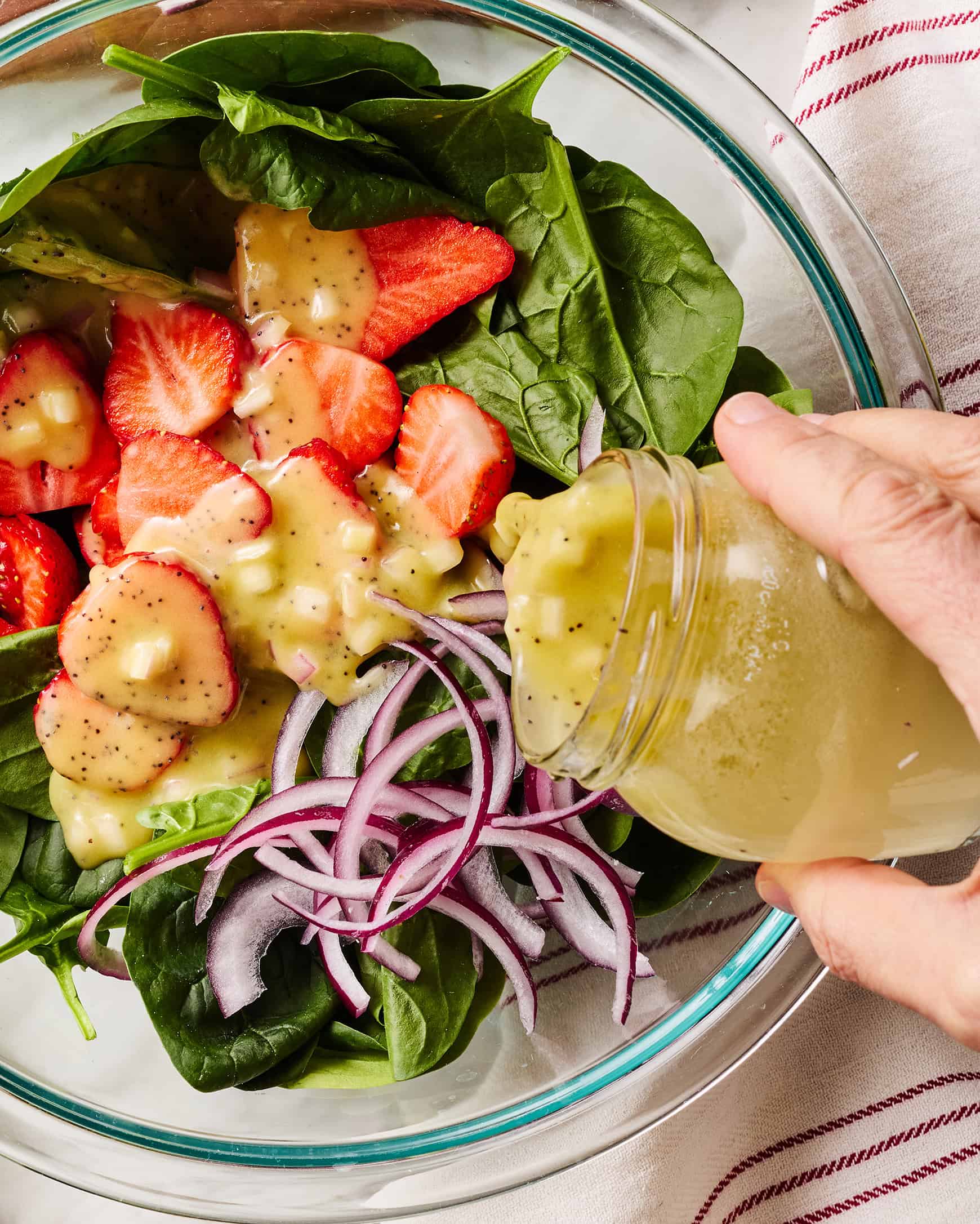 Pouring poppy seed dressing over salad