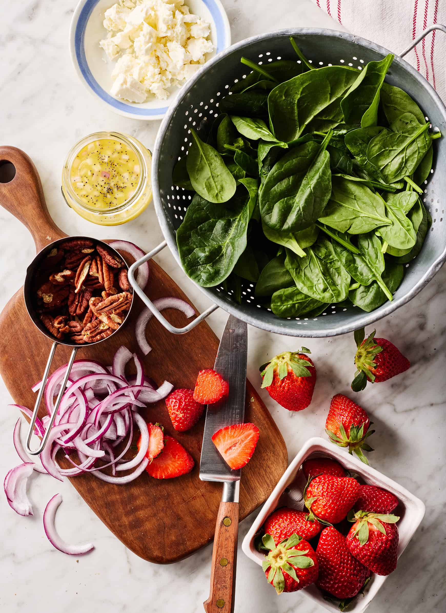 Salad ingredients - spinach, strawberries, feta, pecans, red onion, and poppy seed dressing