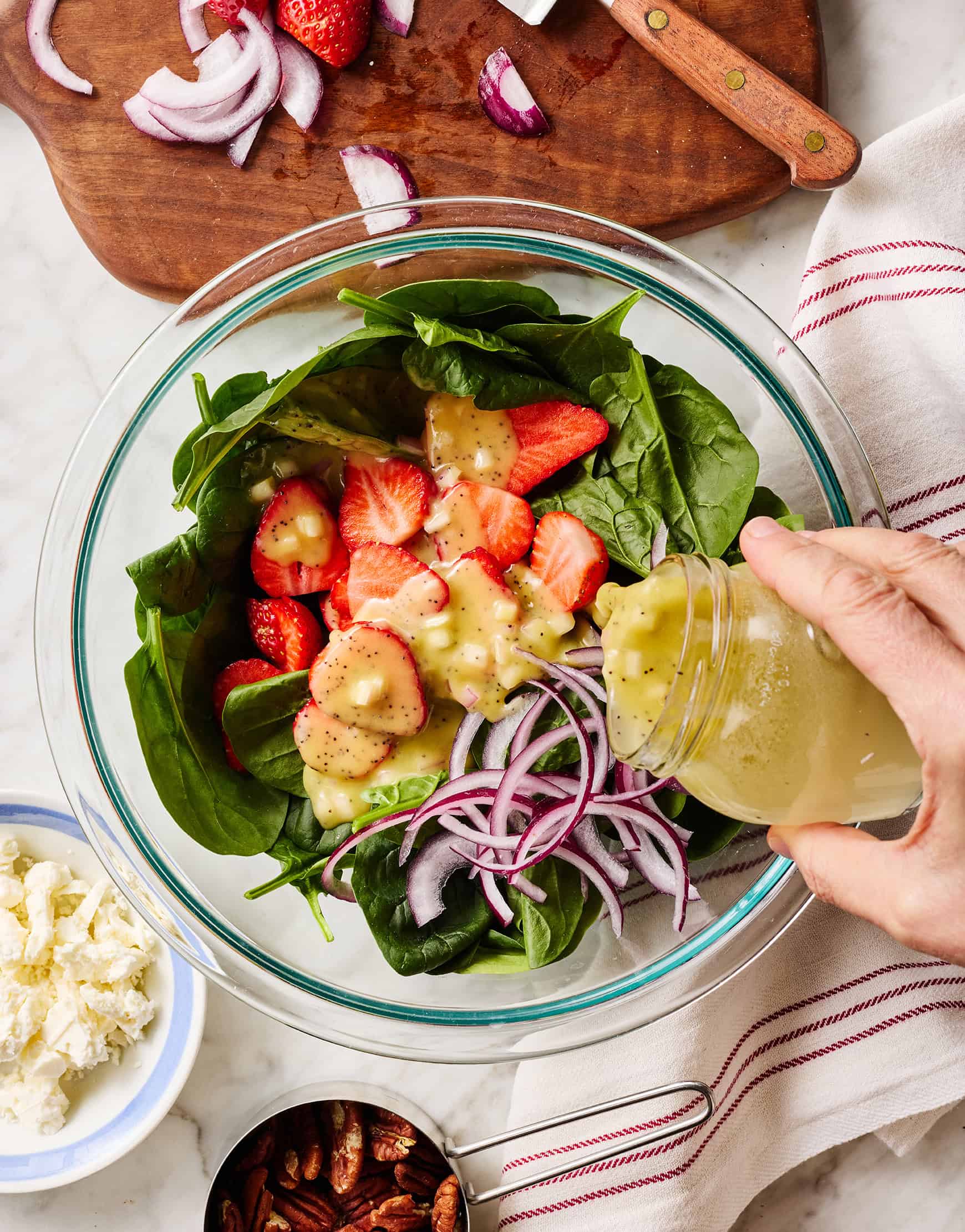 Pouring dressing over strawberry spinach salad