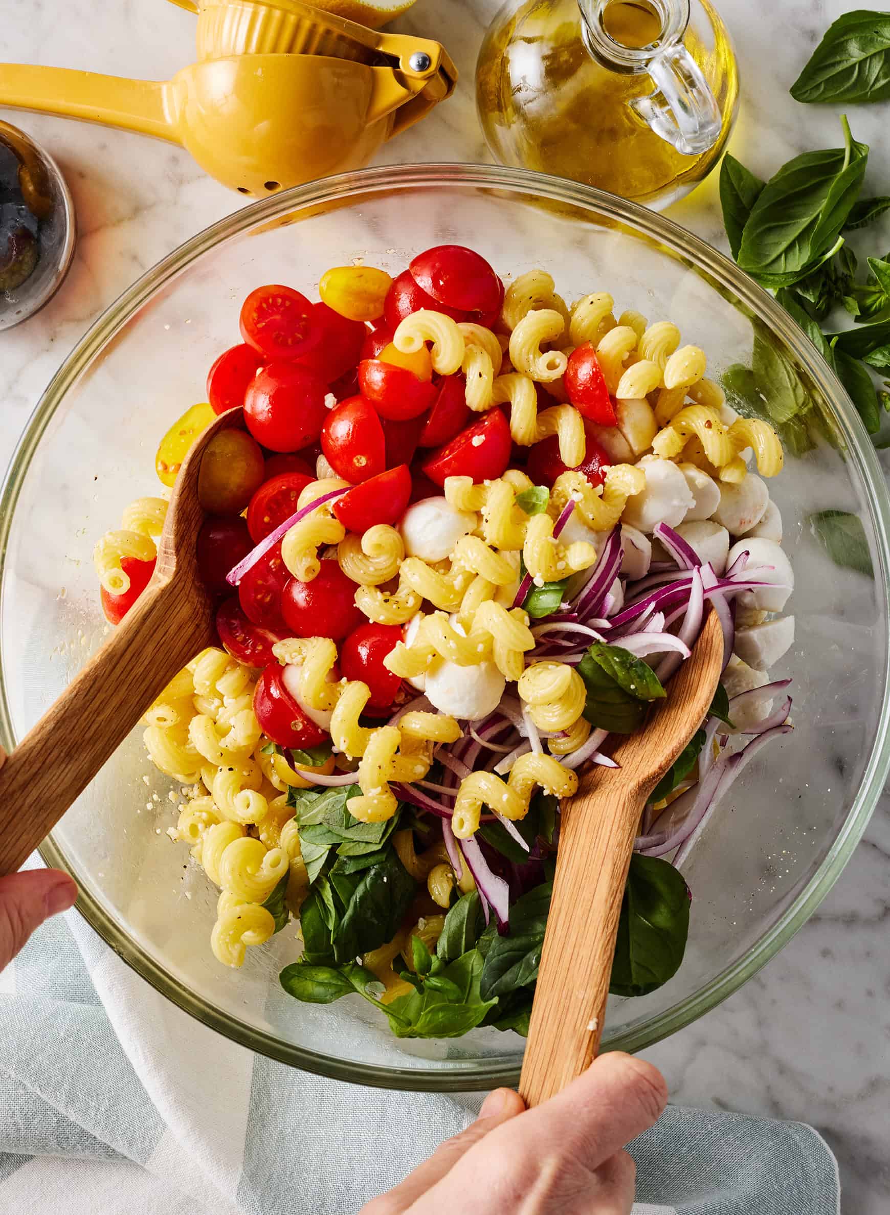 Tossing Caprese pasta salad in mixing bowl