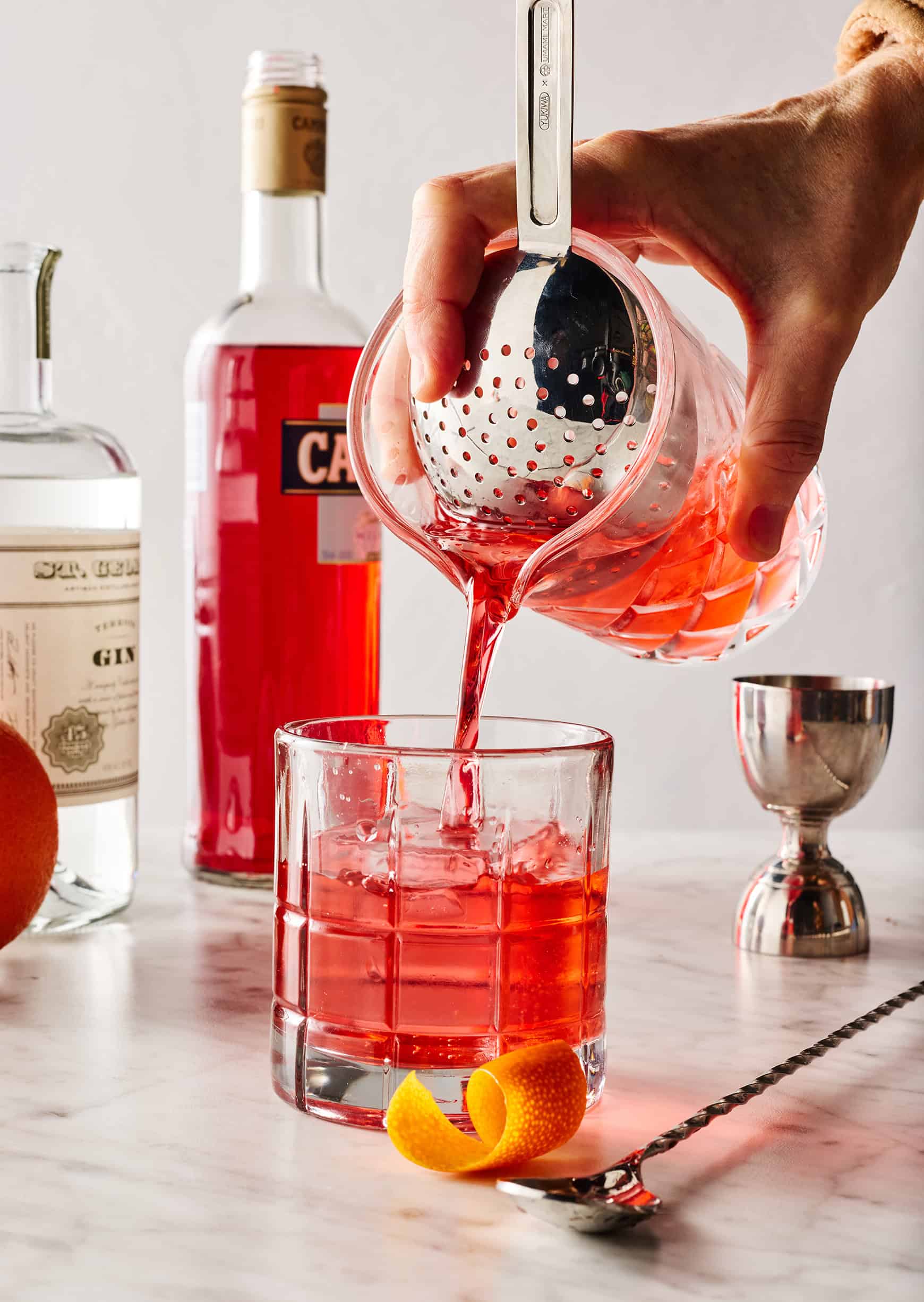 Straining Negroni into cocktail glass