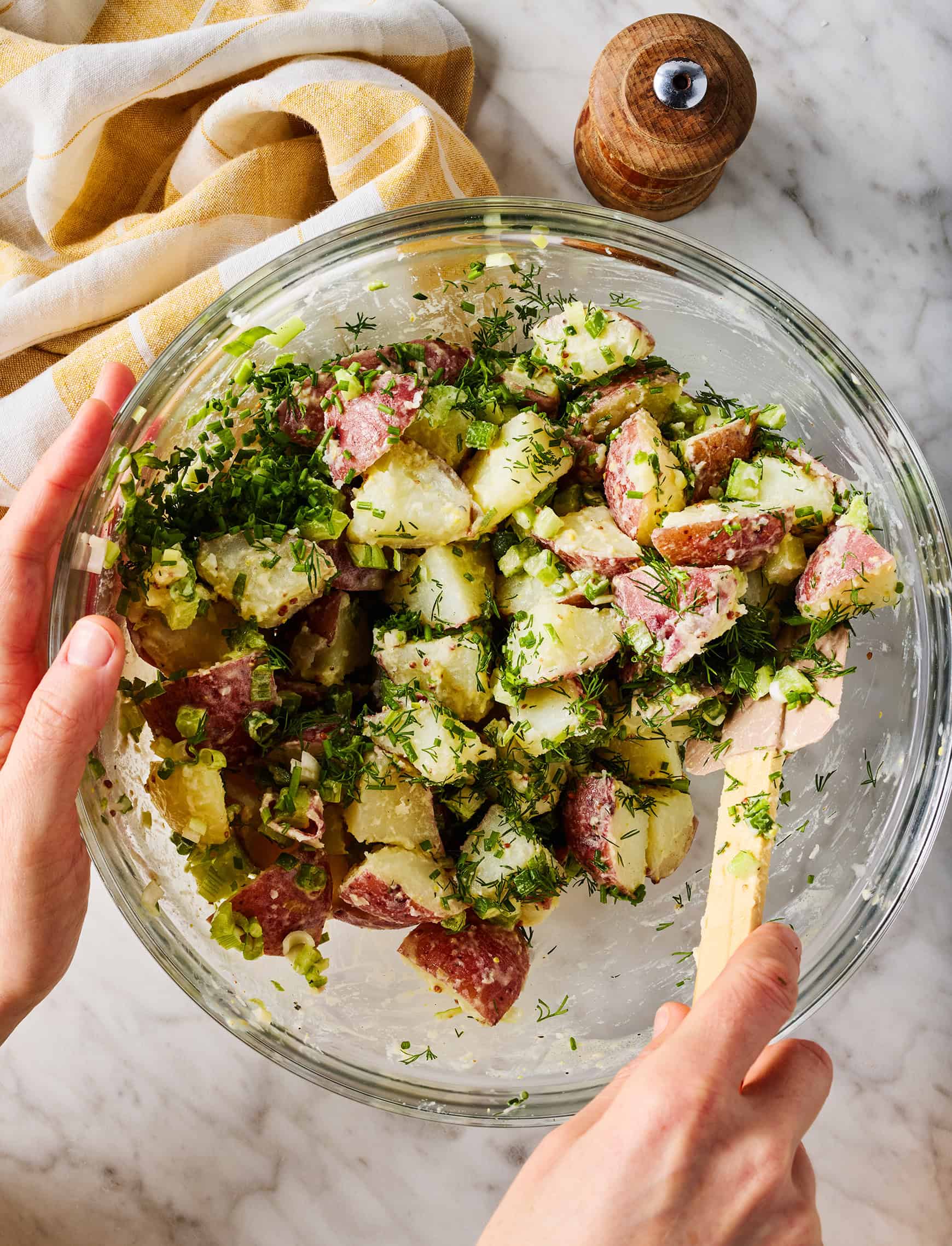 Mixing red potato salad in glass bowl