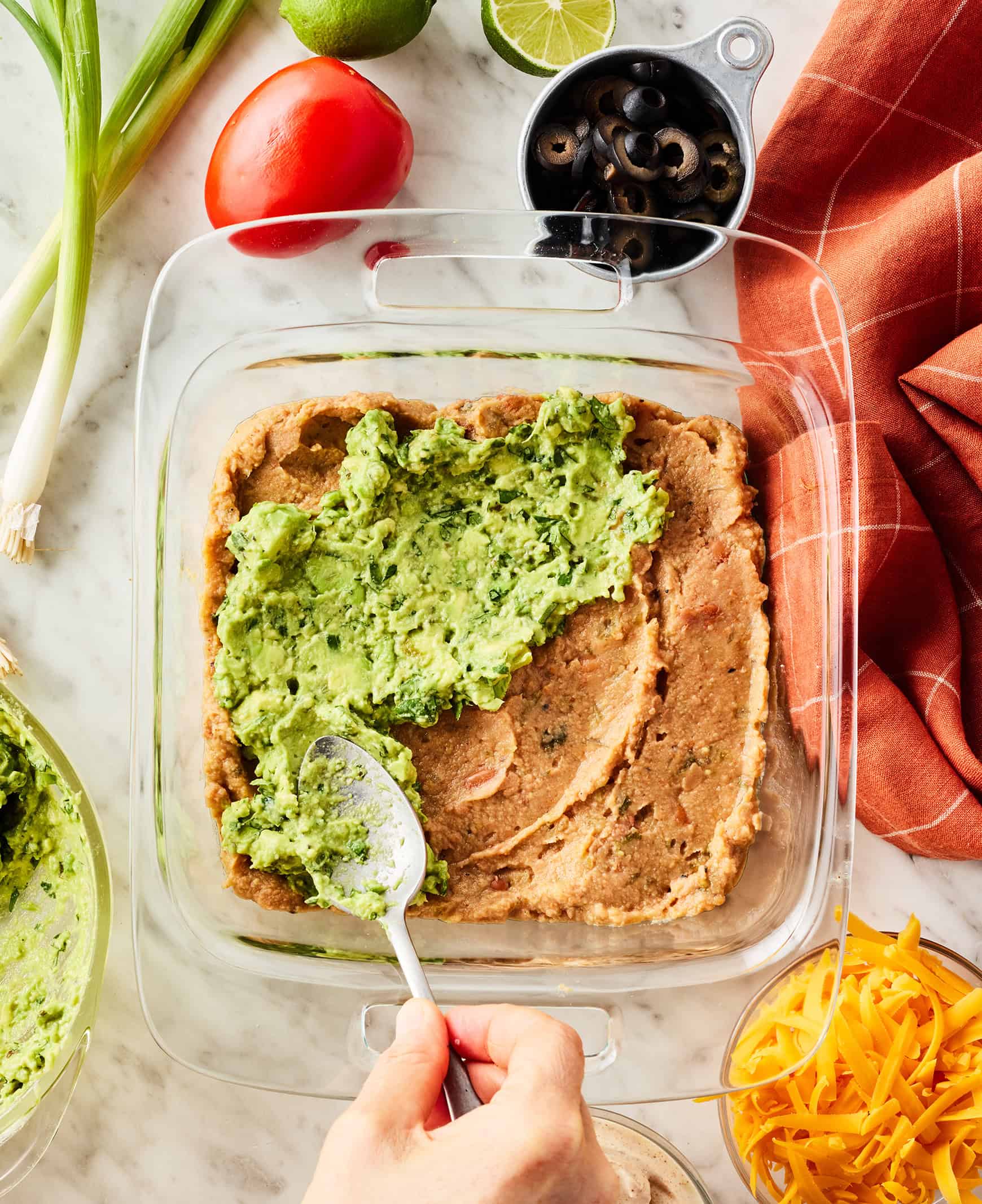 Spreading avocado layer over refried beans