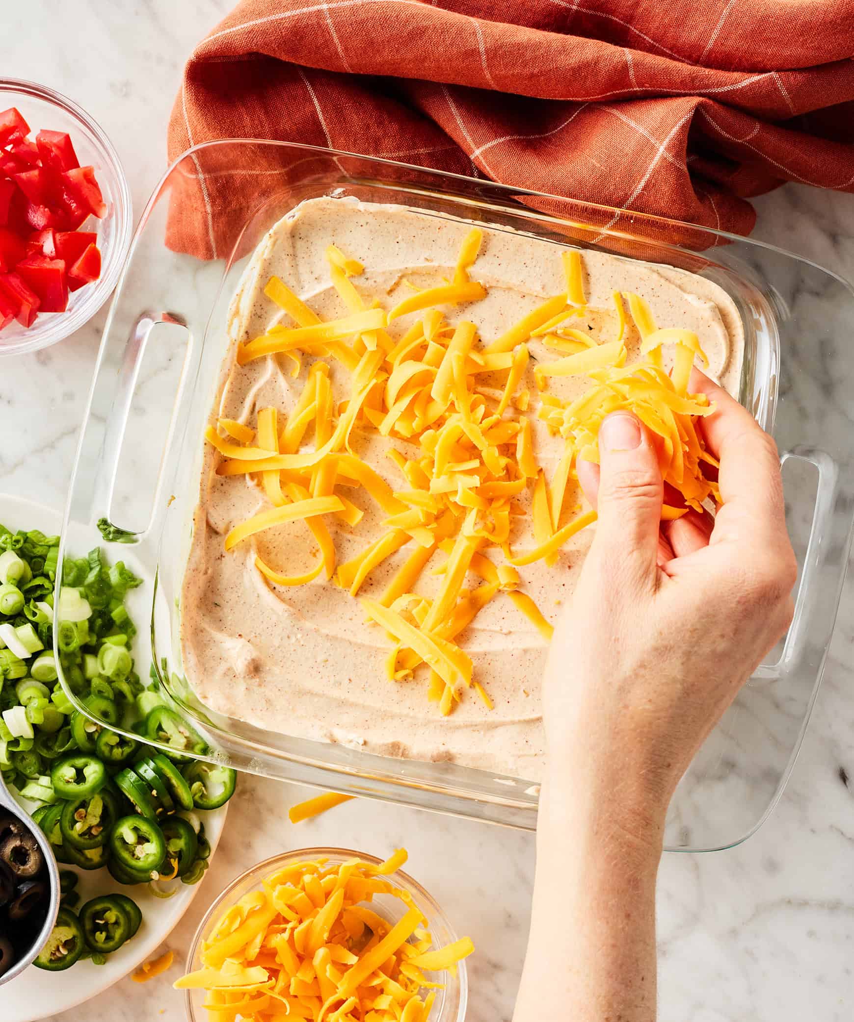 Sprinkling cheddar cheese over sour cream layer