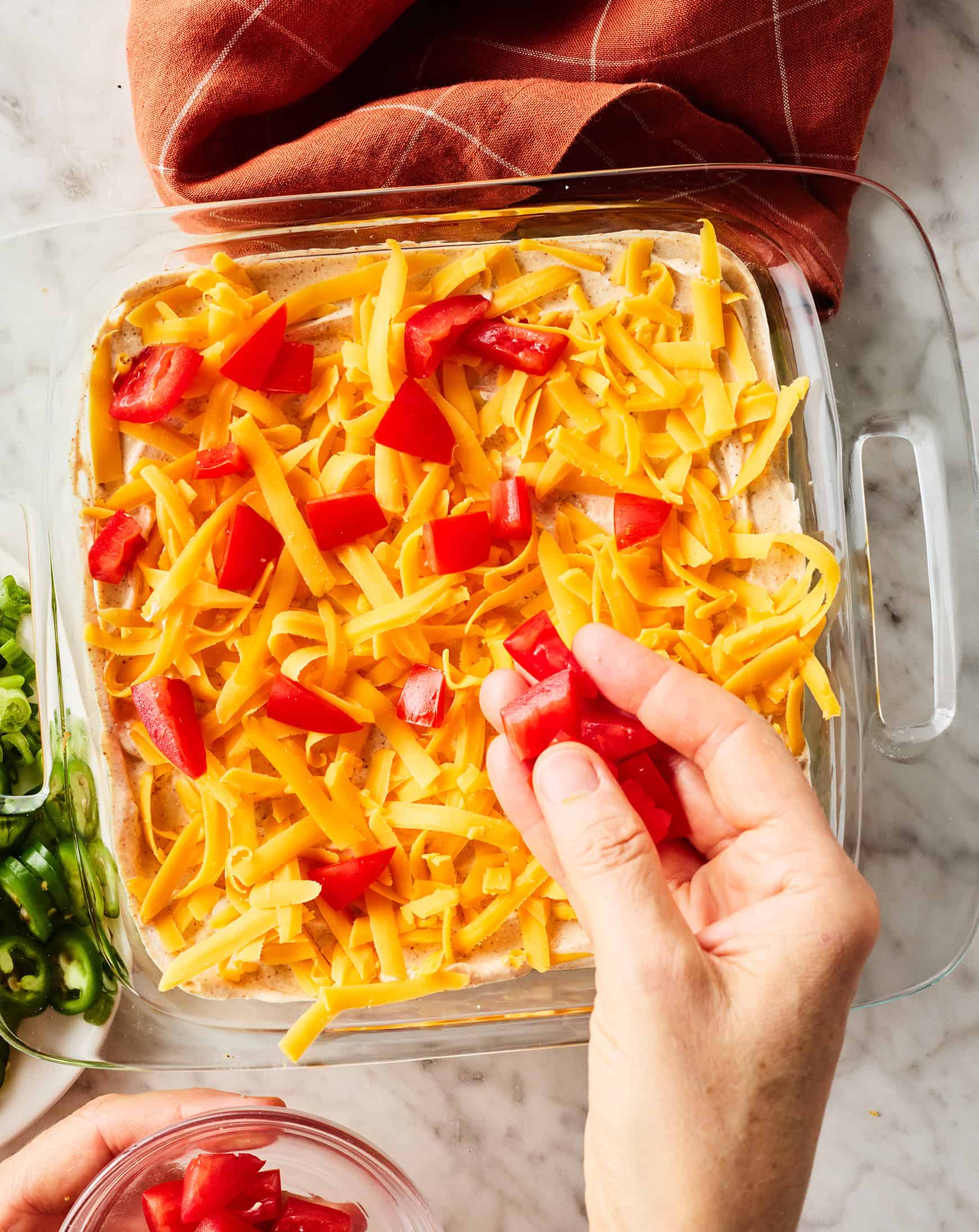 Adding chopped tomatoes to seven layer dip