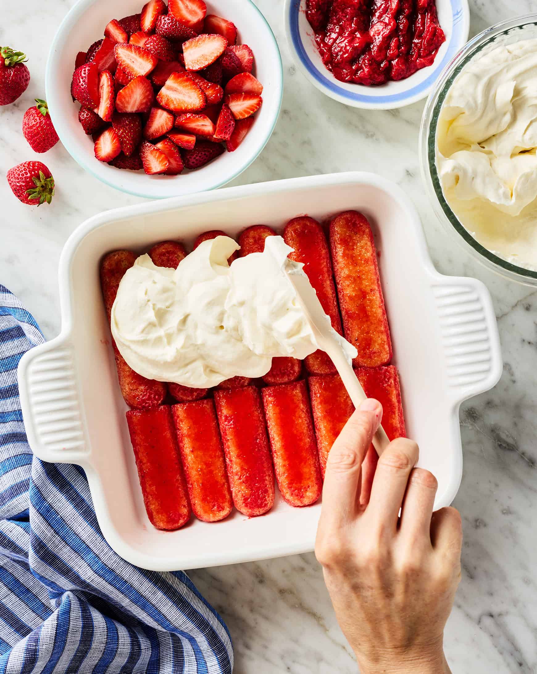 Spreading whipped cream and mascarpone on top of ladyfingers