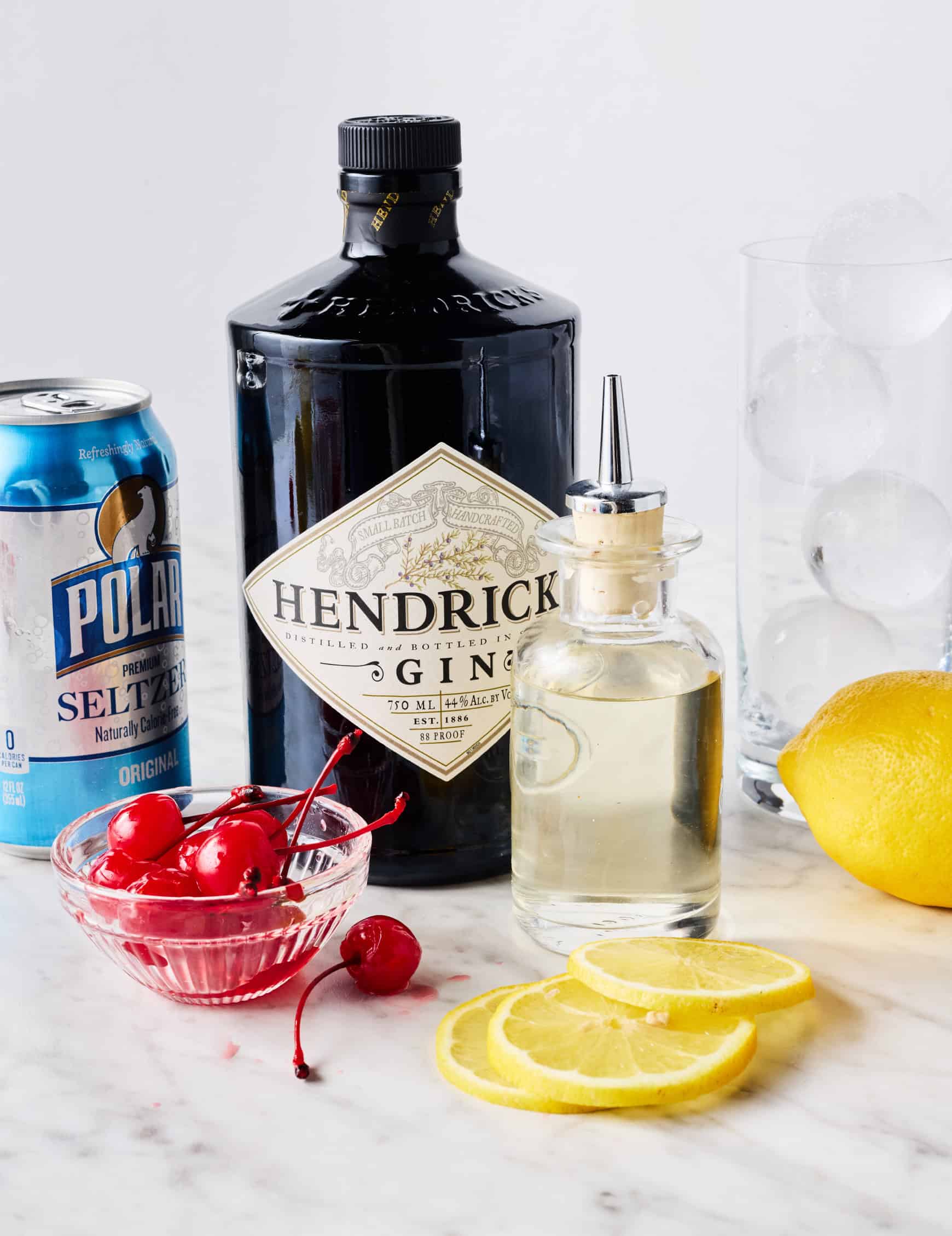 Gin, simple syrup, sparkling water, ice, fresh lemons, and maraschino cherries