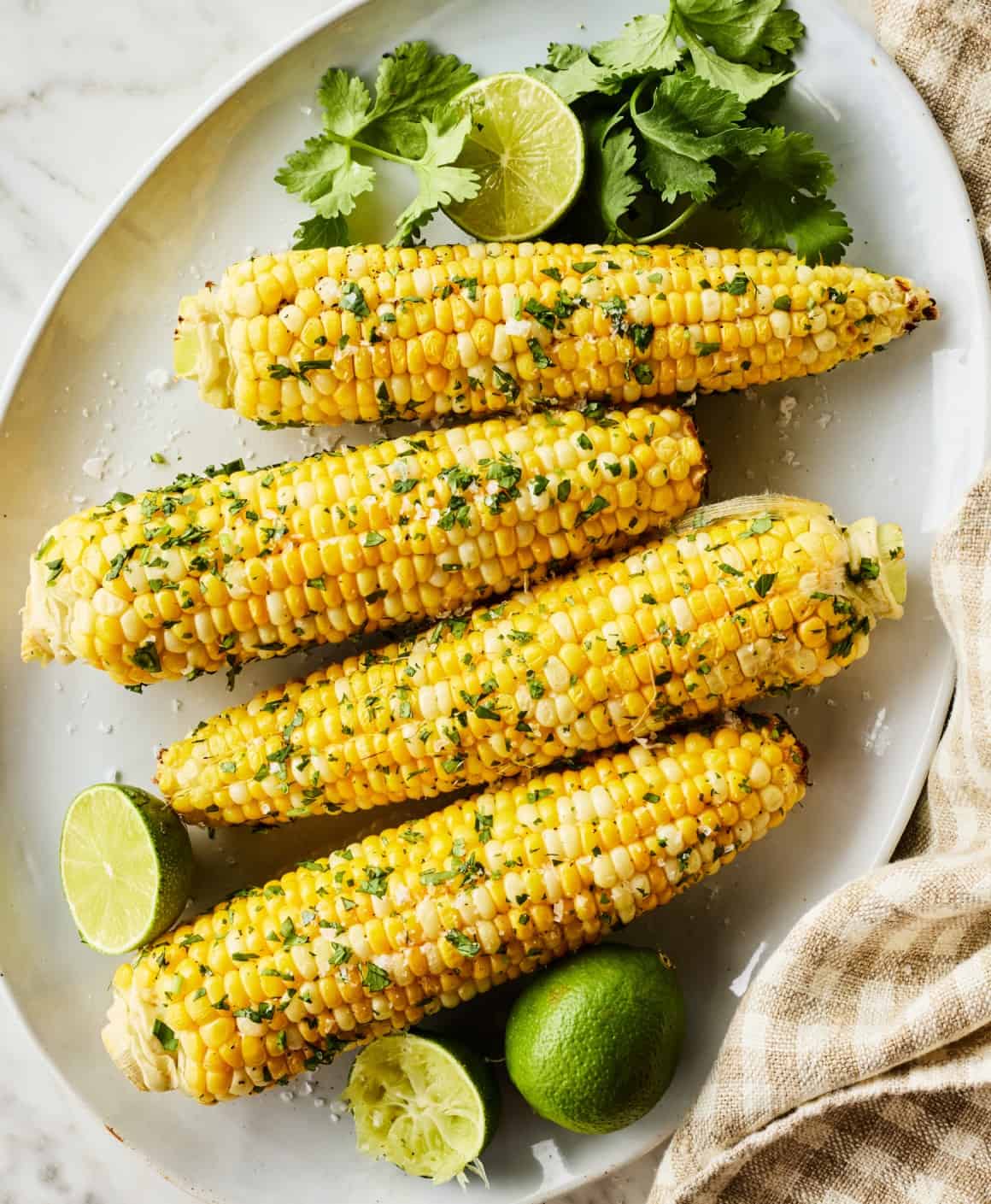 Air fryer corn on the cob with herb butter and charred kernels on a summer plate