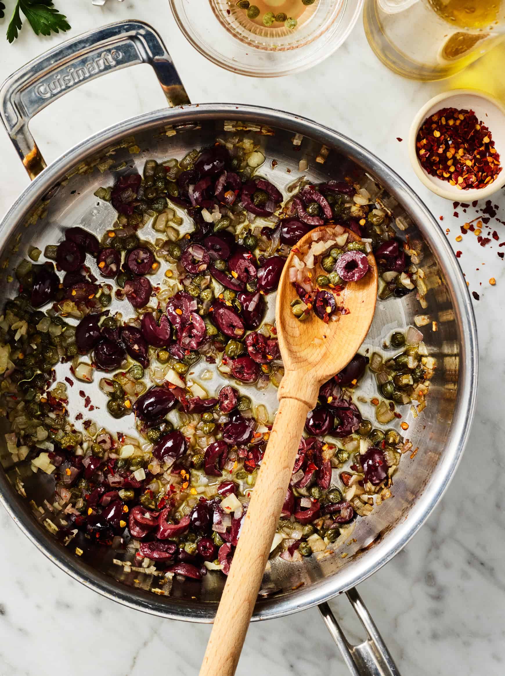 Cooking capers, olives, garlic, and red pepper flakes in large skillet