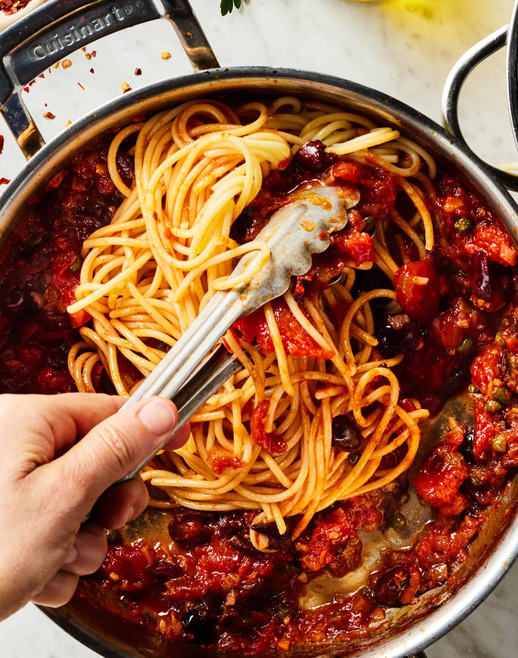 Tossing spaghetti with puttanesca sauce