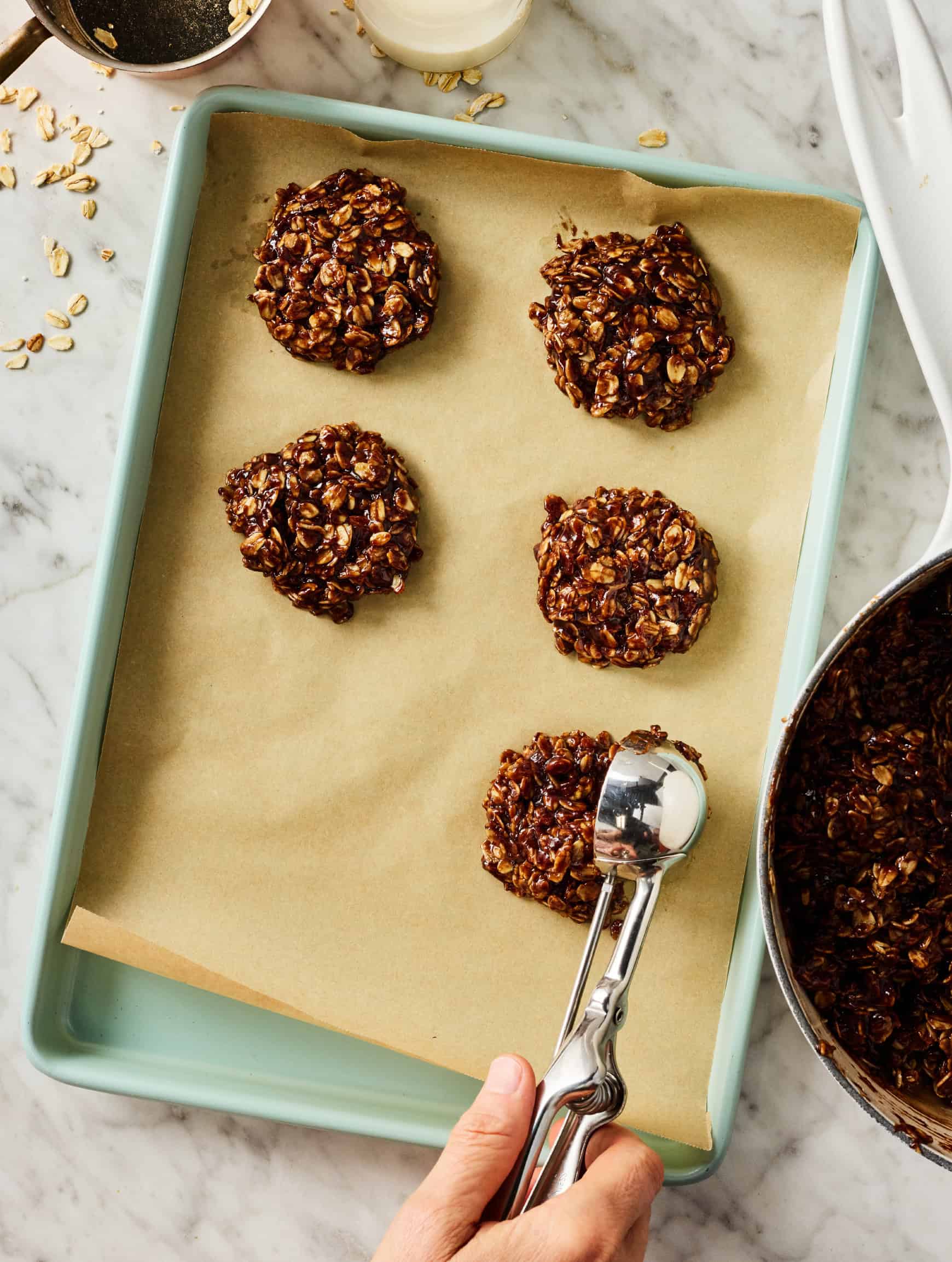 Scooping chocolate peanut butter no bake cookies onto baking sheet