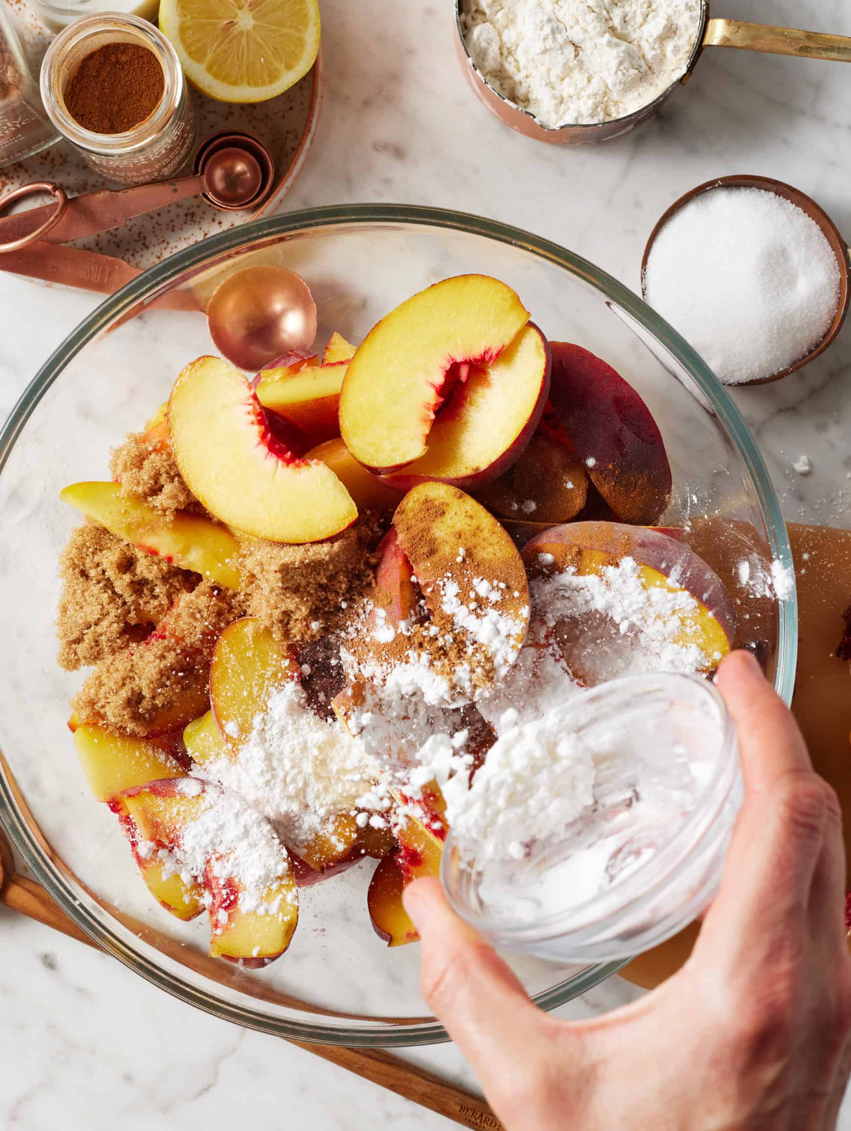 Sprinkling cornstarch over sliced peaches