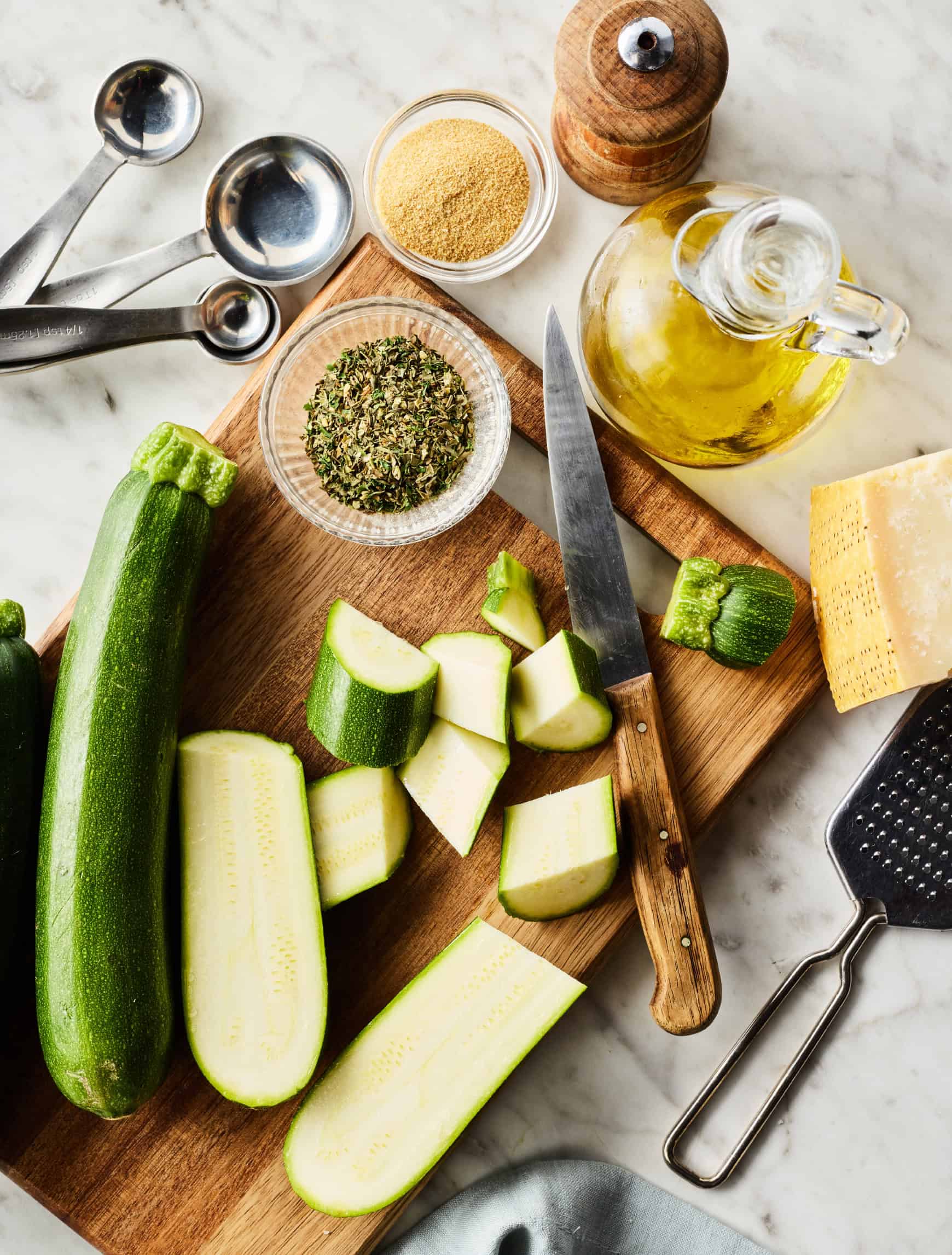 Chopped zucchini on cutting board next to seasonings