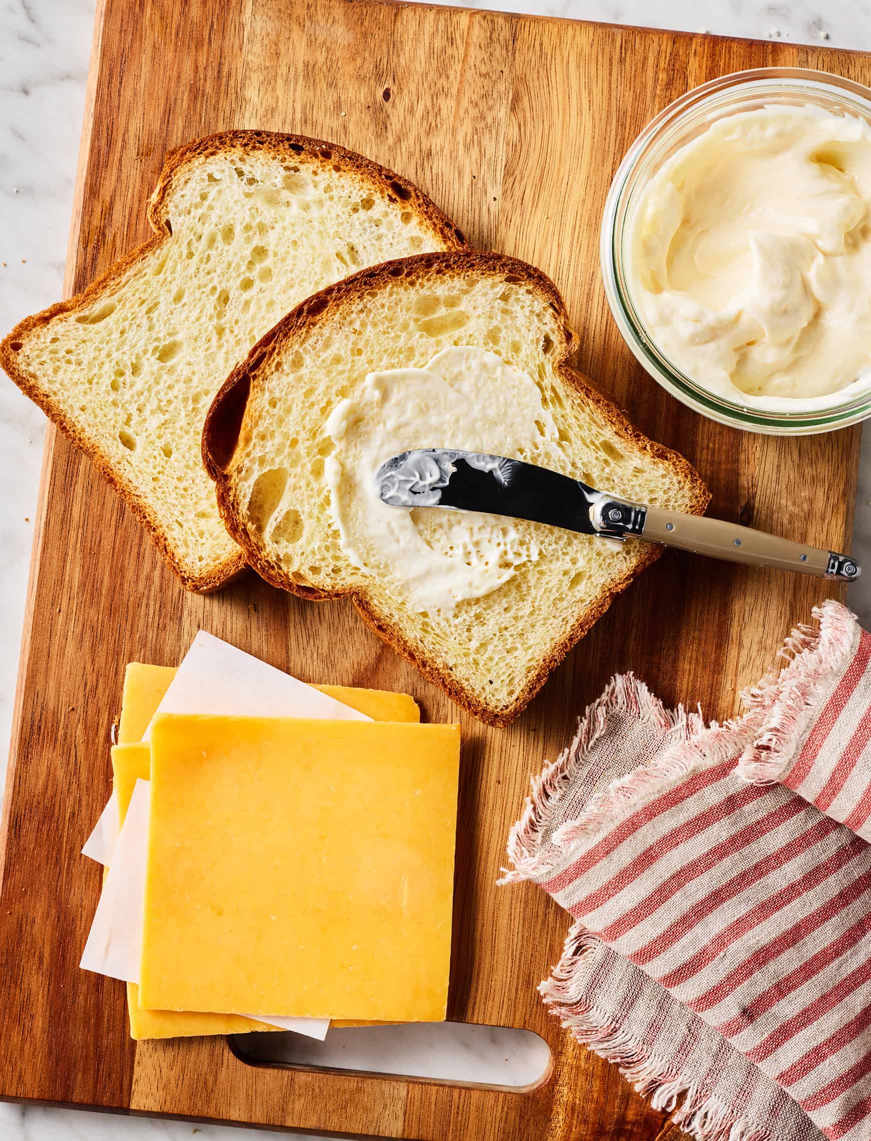 Recipe ingredients - sliced bread, sliced cheese, and mayo on cutting board