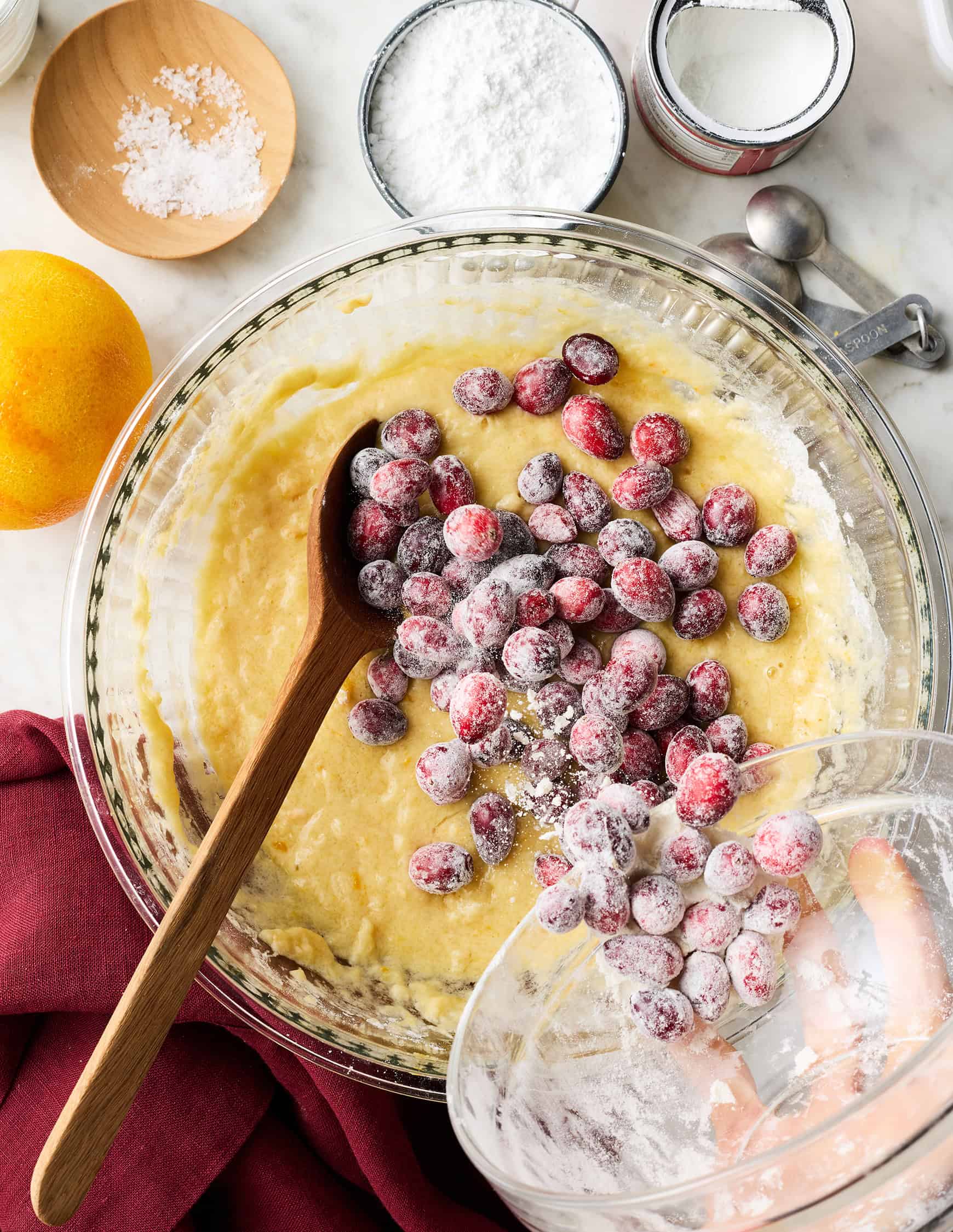 Pouring fresh cranberries into bowl with batter