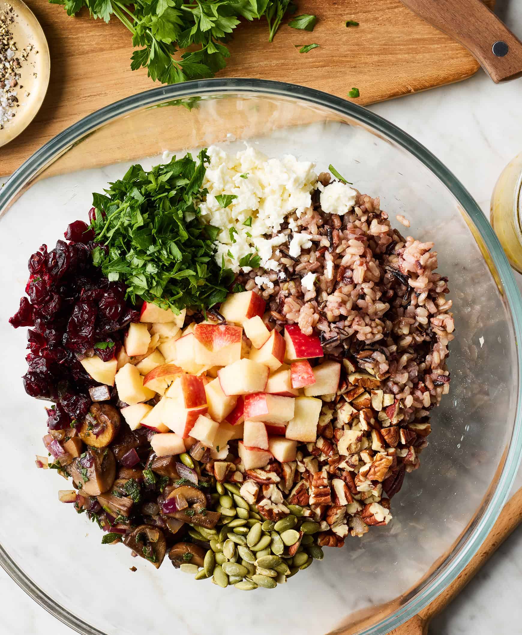 Wild rice, apples, dried cranberries, mushrooms, herbs, feta, and pepitas in a bowl
