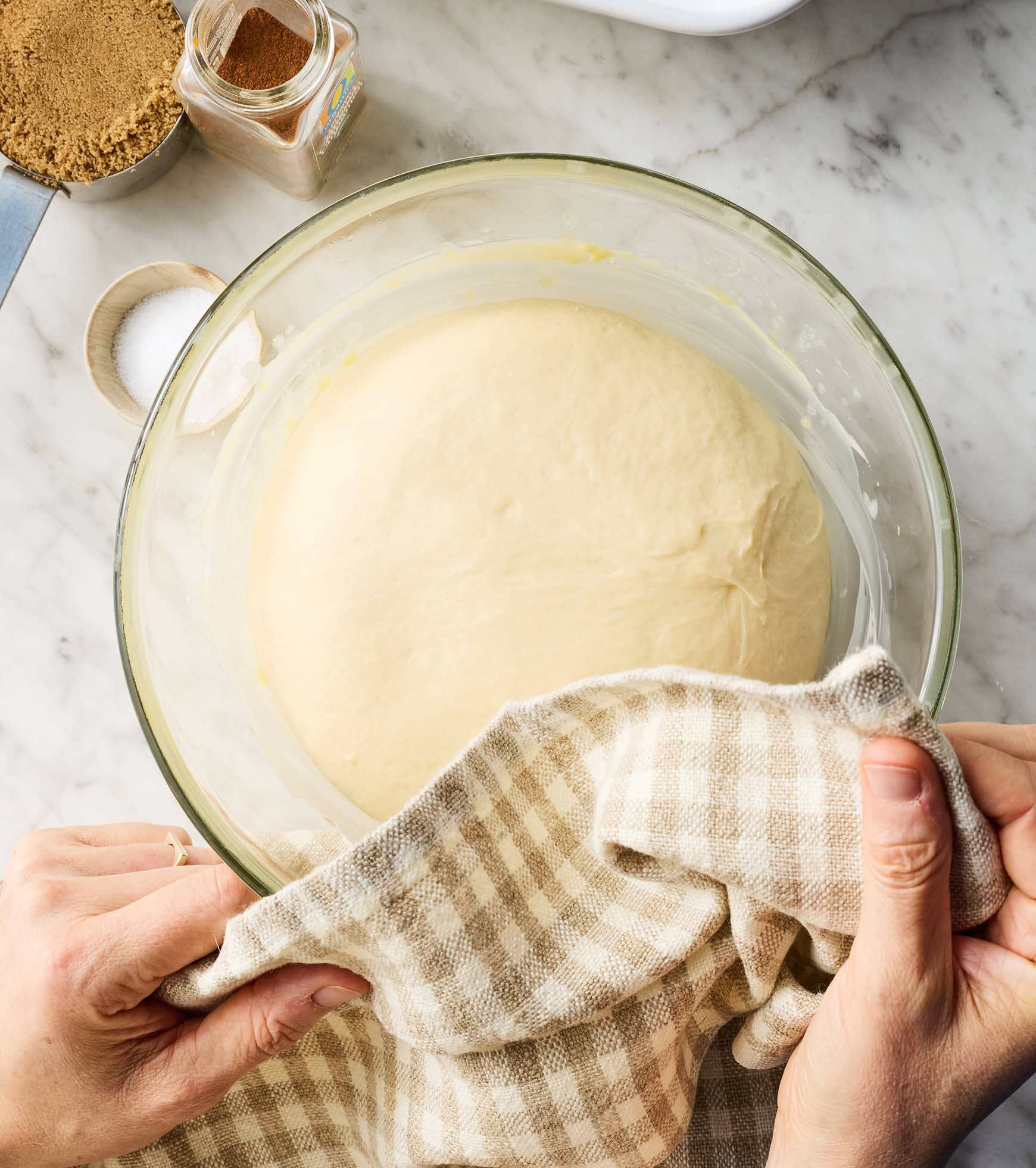 Hands placing kitchen towel over dough ball in large bowl
