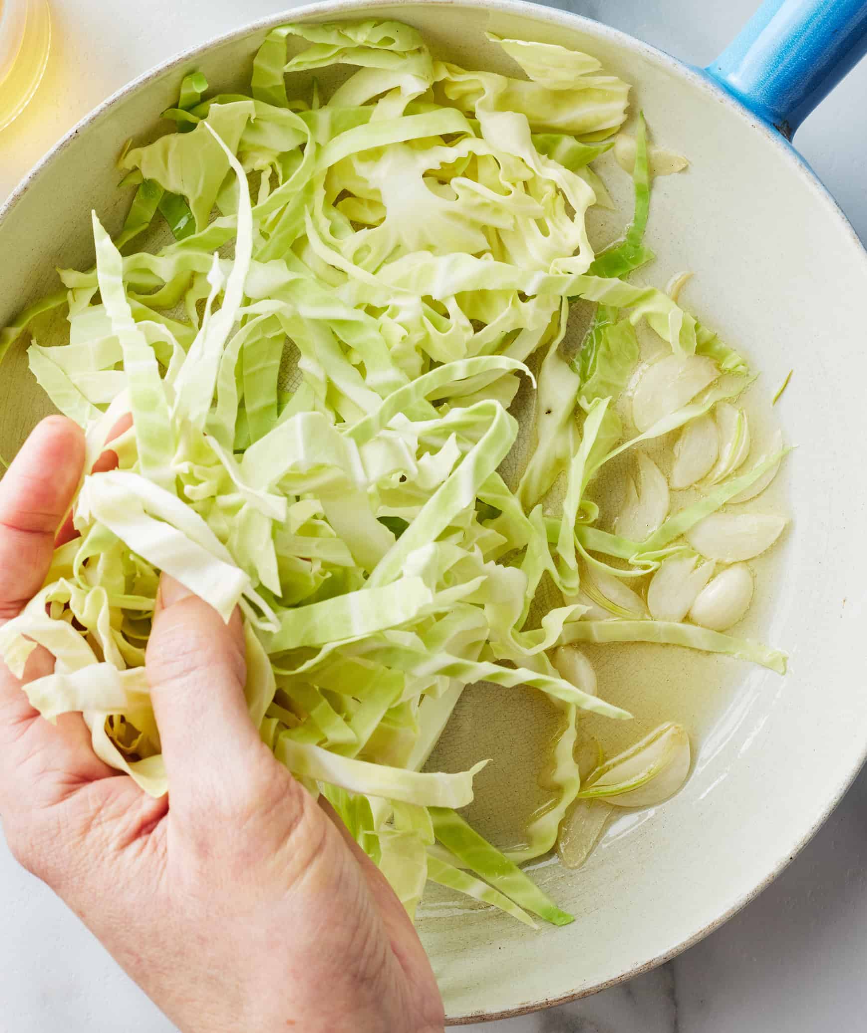 Adding sliced cabbage to skillet