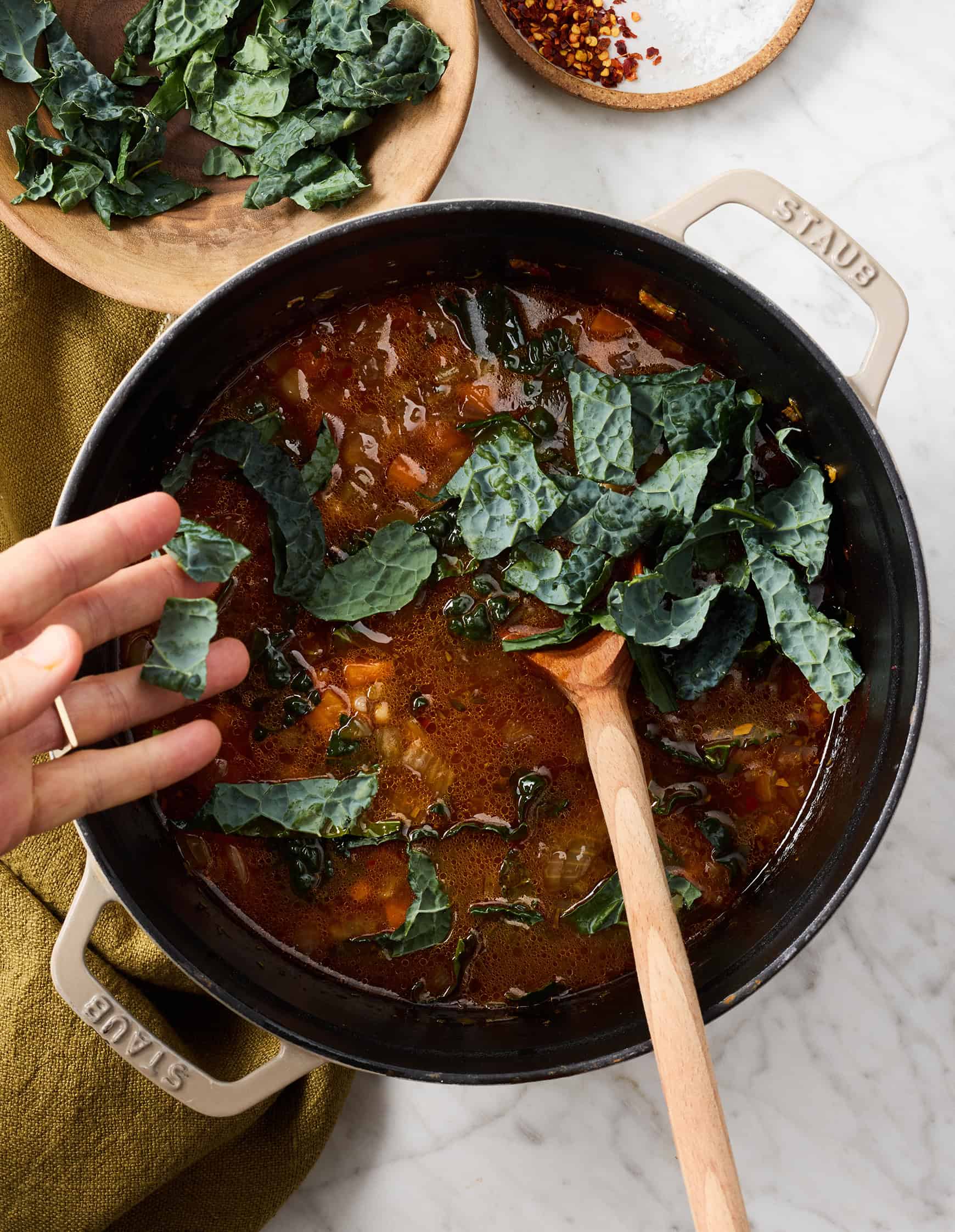 Adding kale leaves to pot of soup