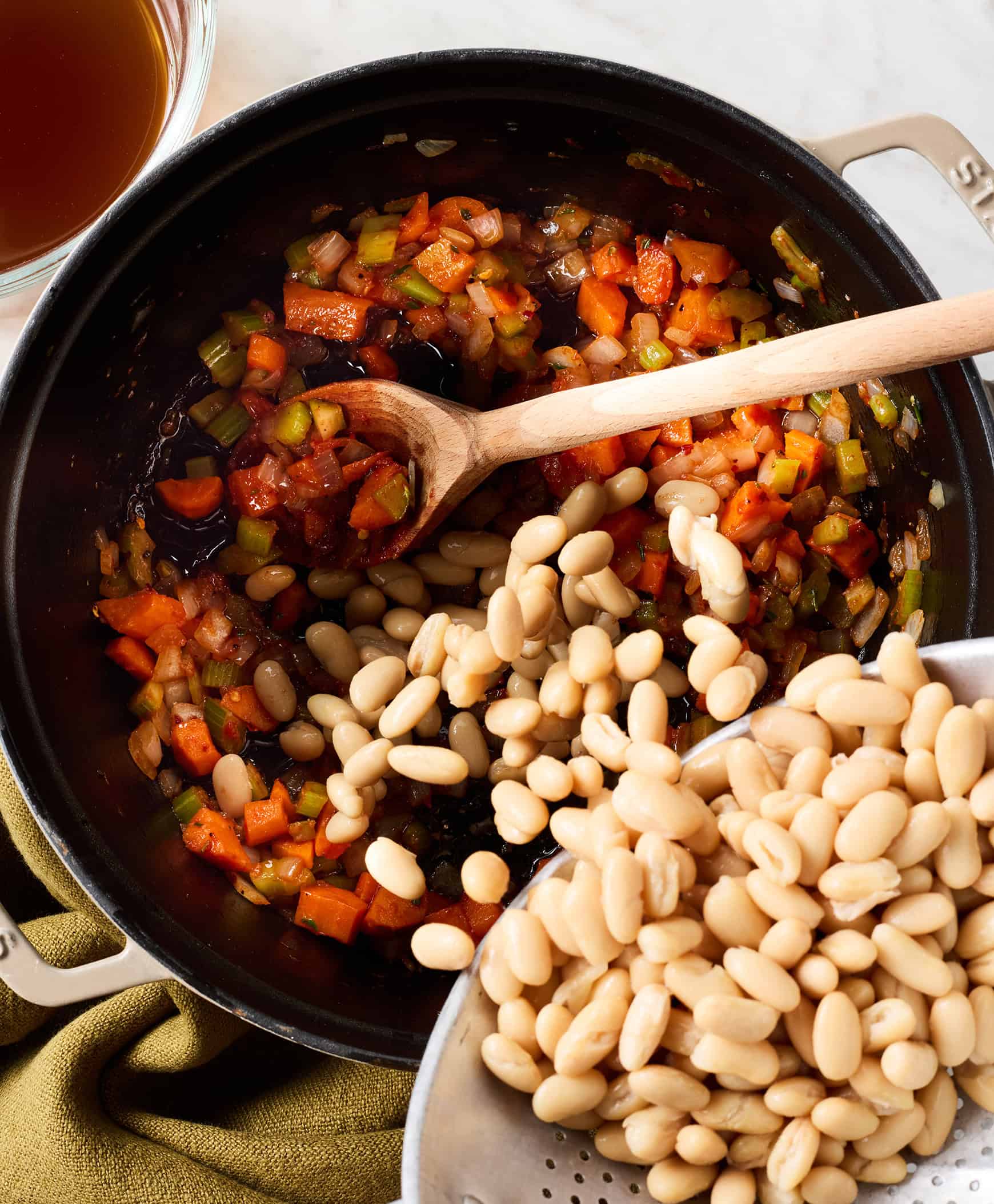 Adding beans to pot with sautéed vegetables