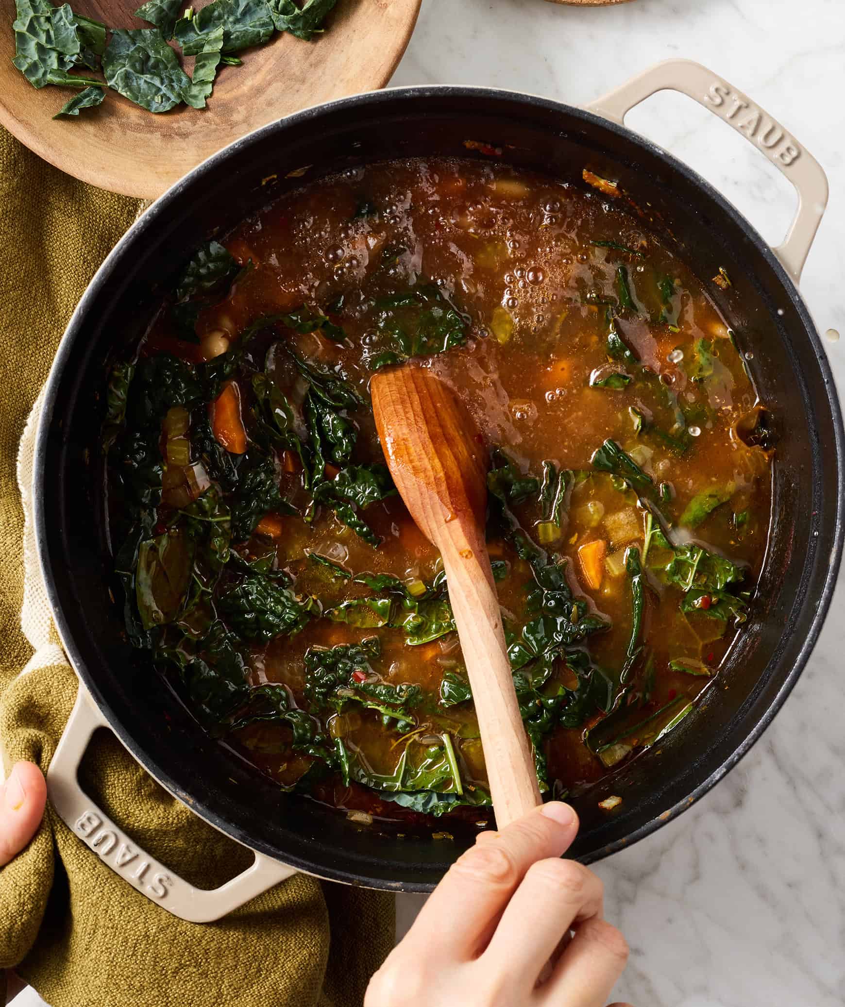 Stirring white bean and kale soup in pot