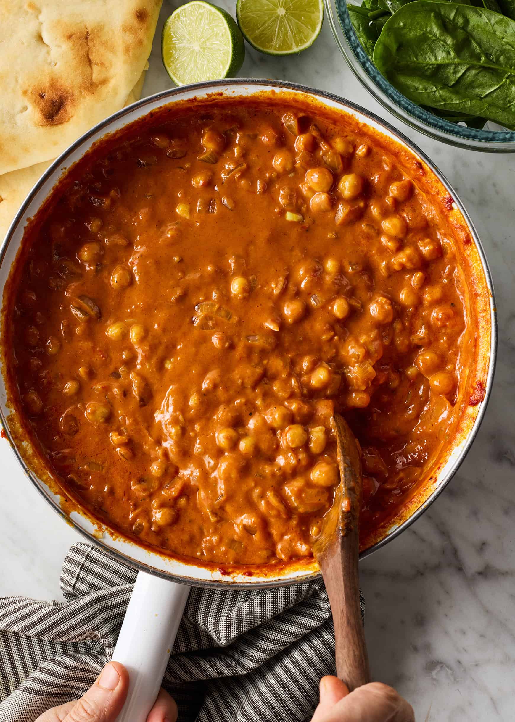 Stirring coconut chickpea curry in skillet