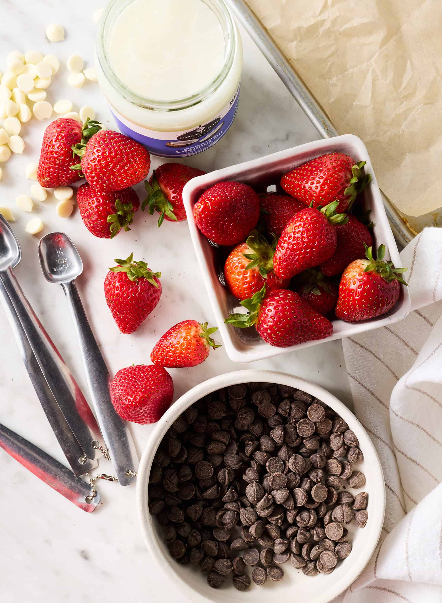 Recipe ingredients - fresh strawberries, chocolate chips, white chocolate chips, and coconut oil
