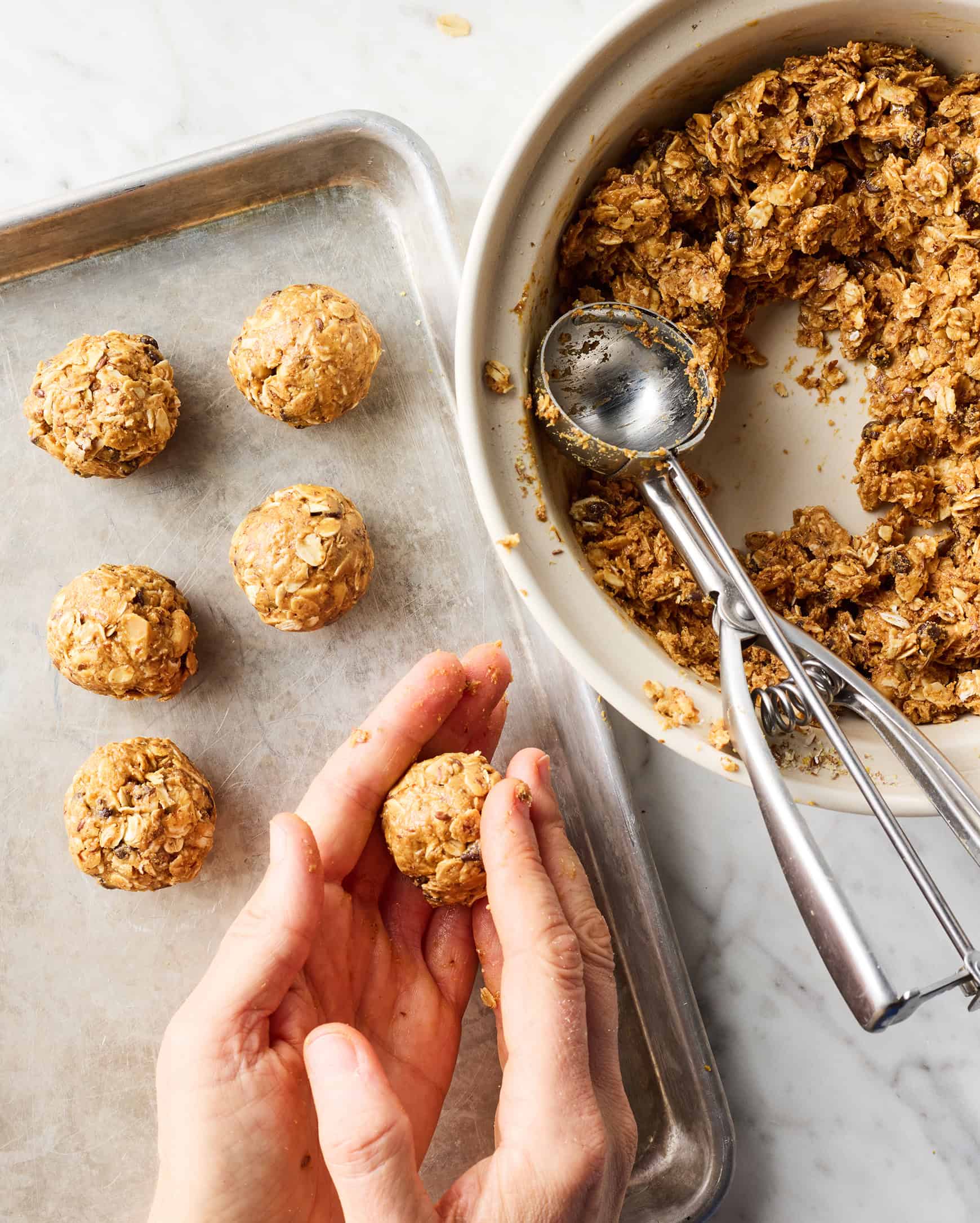 Hands rolling oat and peanut butter mixture into balls