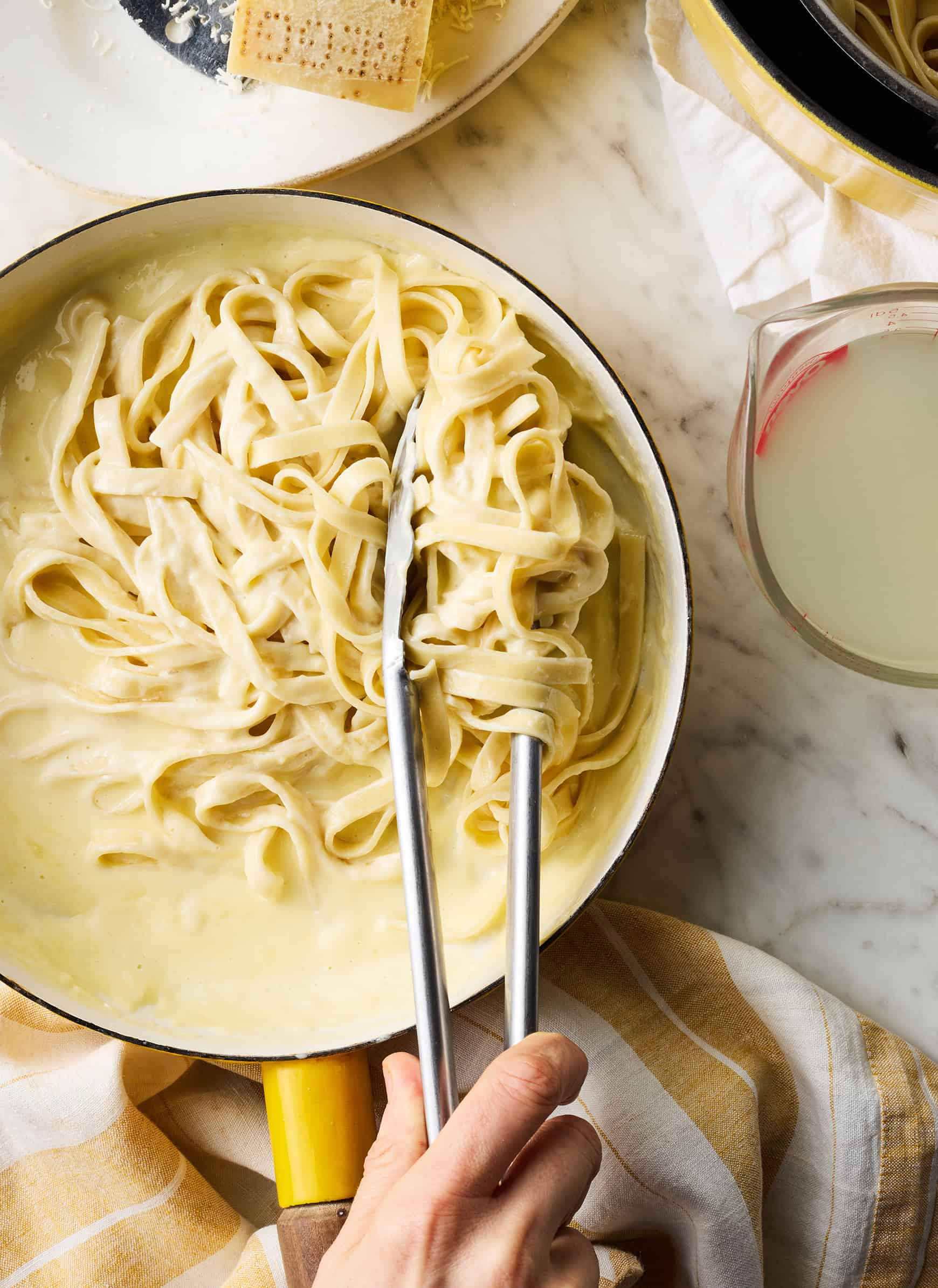 Tossing pasta with homemade Alfredo sauce in skillet