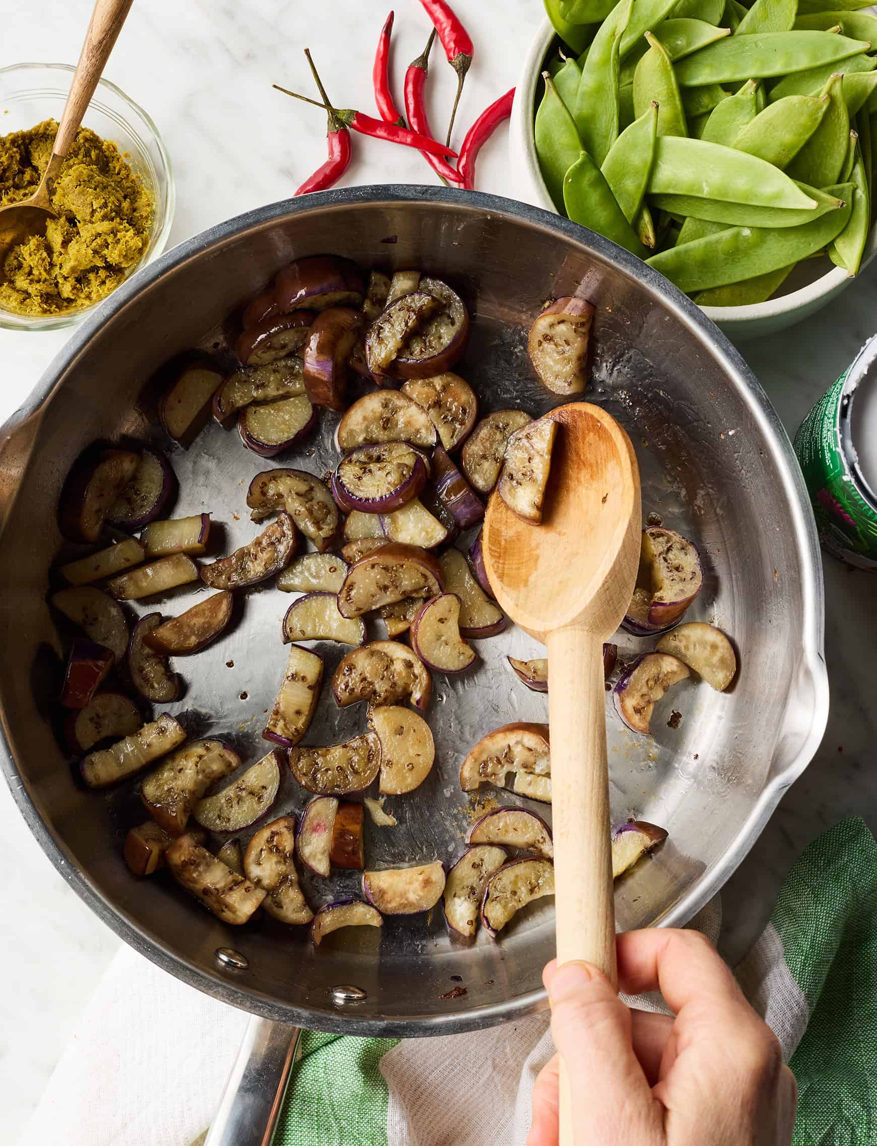 Sautéing eggplant in skillet with wooden spoon