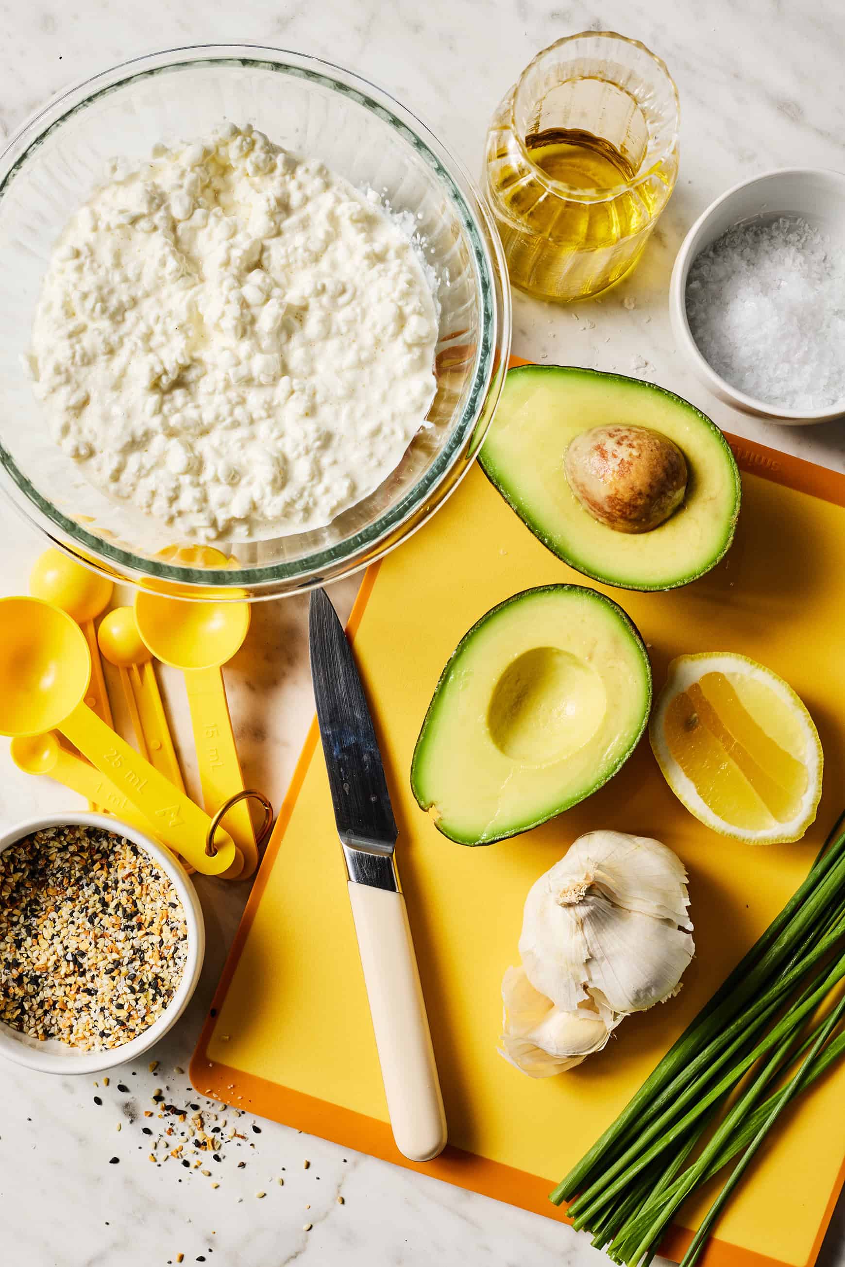 Recipe ingredients - cottage cheese, avocado, garlic, lemon, olive oil, sea salt, everything bagel seasoning, and chives