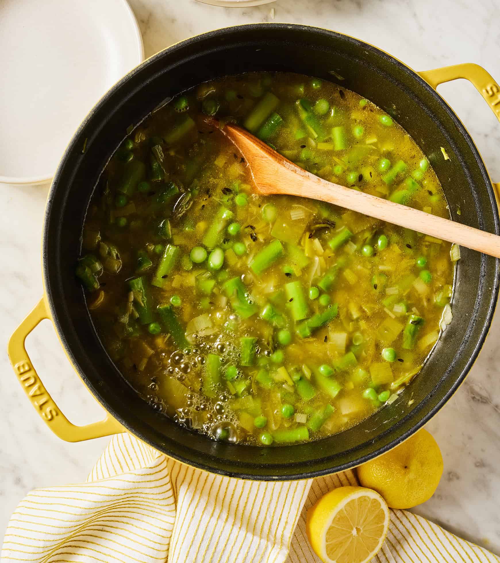 Simmering asparagus soup in pot with wooden spoon