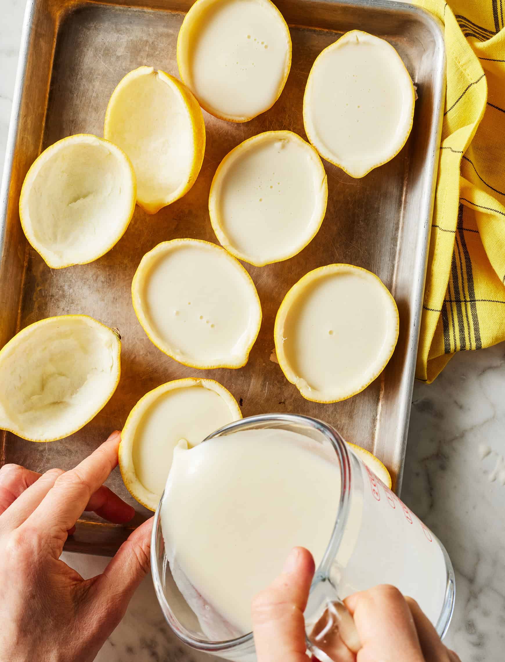 Pouring lemon posset into lemon halves to set