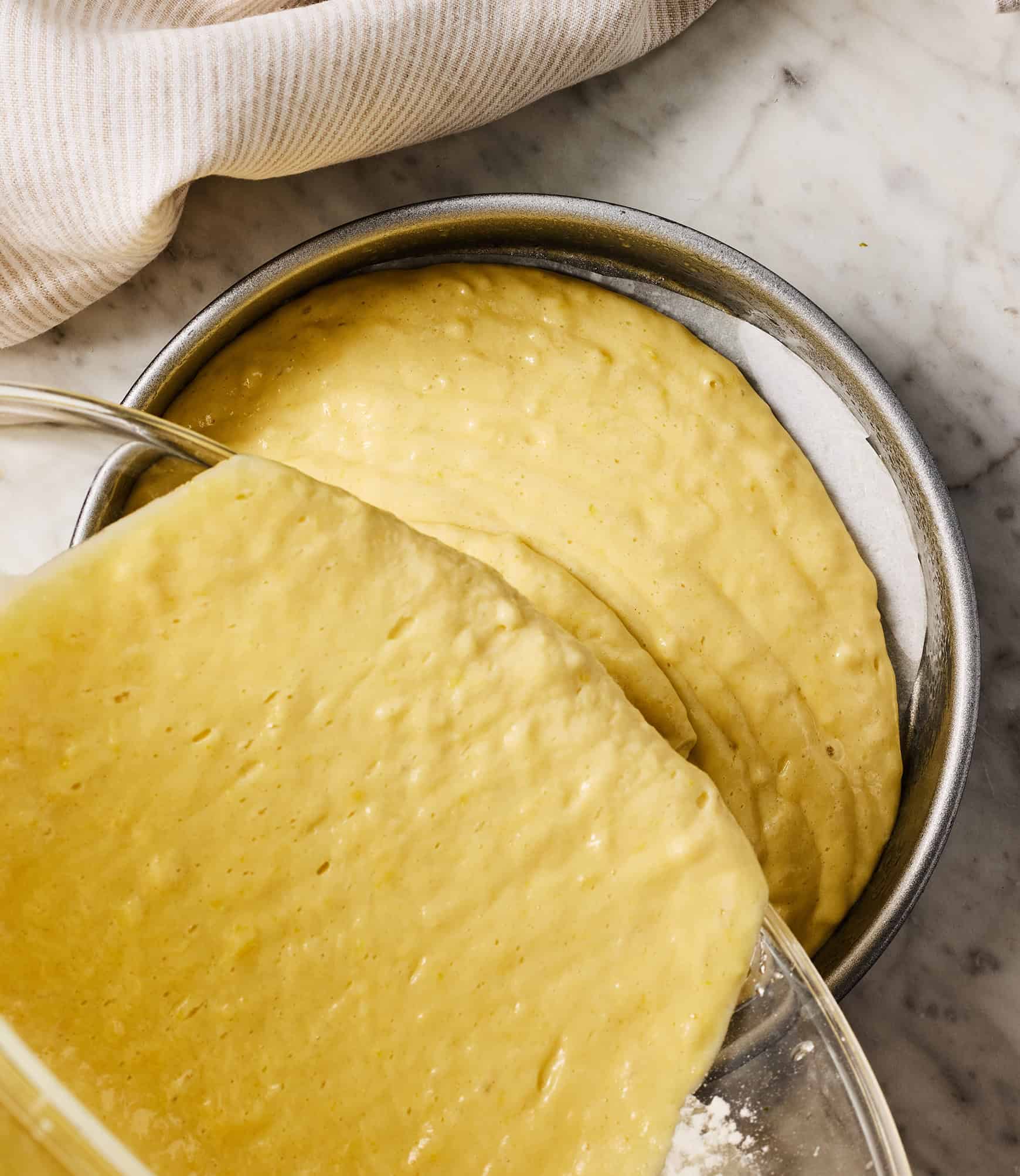 Pouring olive oil cake batter into prepared cake pan