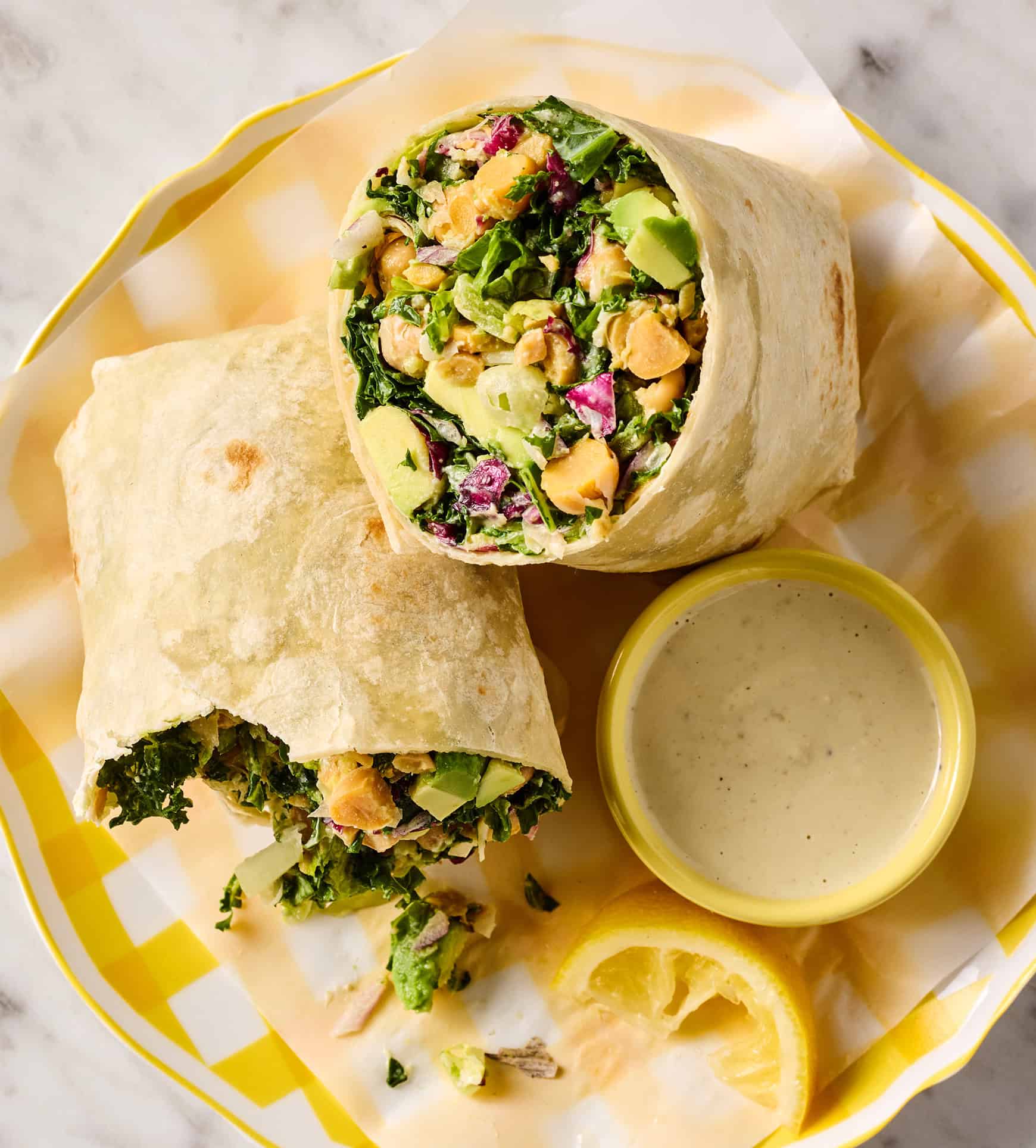 Caesar wrap on plate with dressing on the side