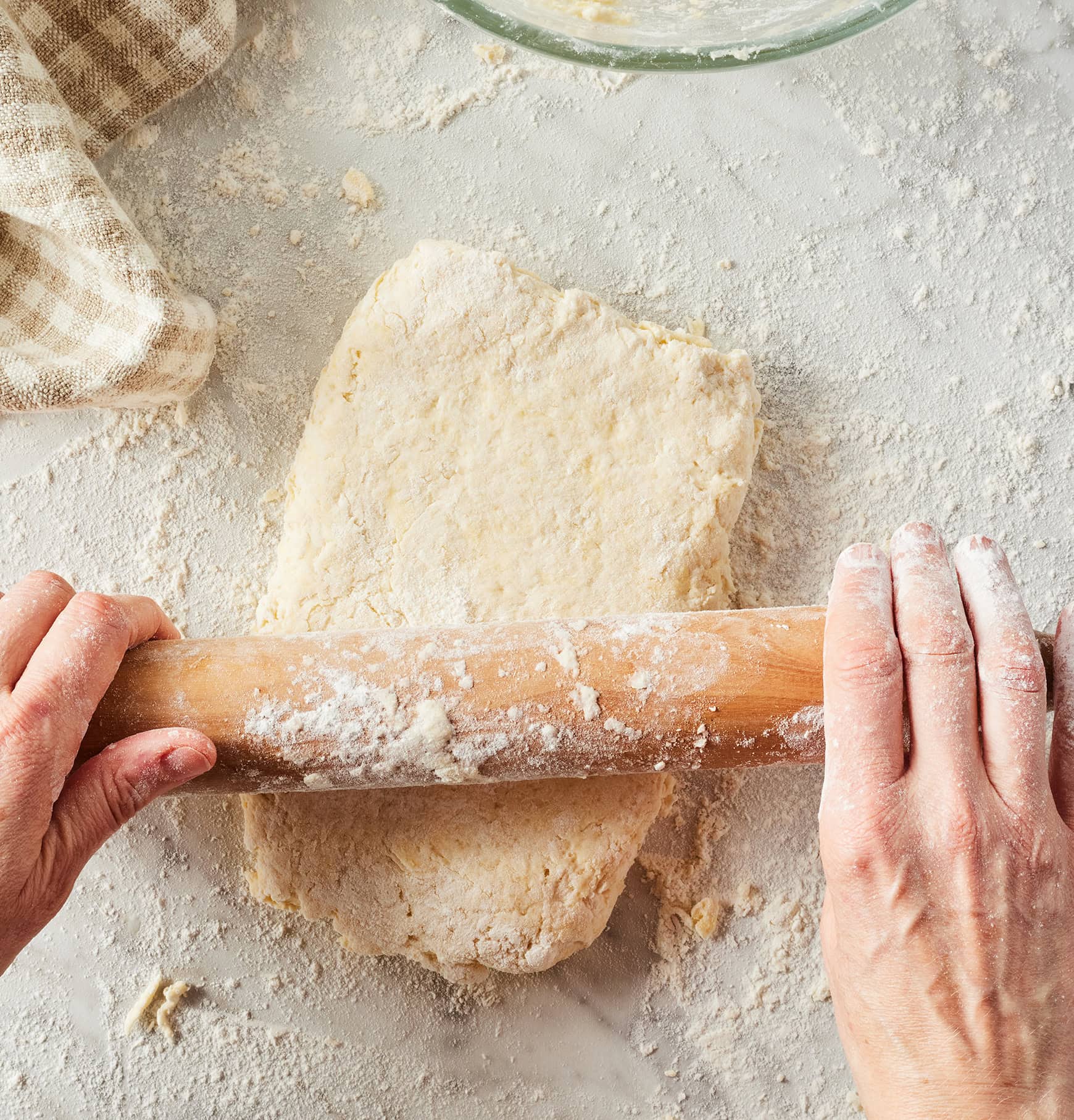 Rolling out strawberry shortcake dough on marble countertop